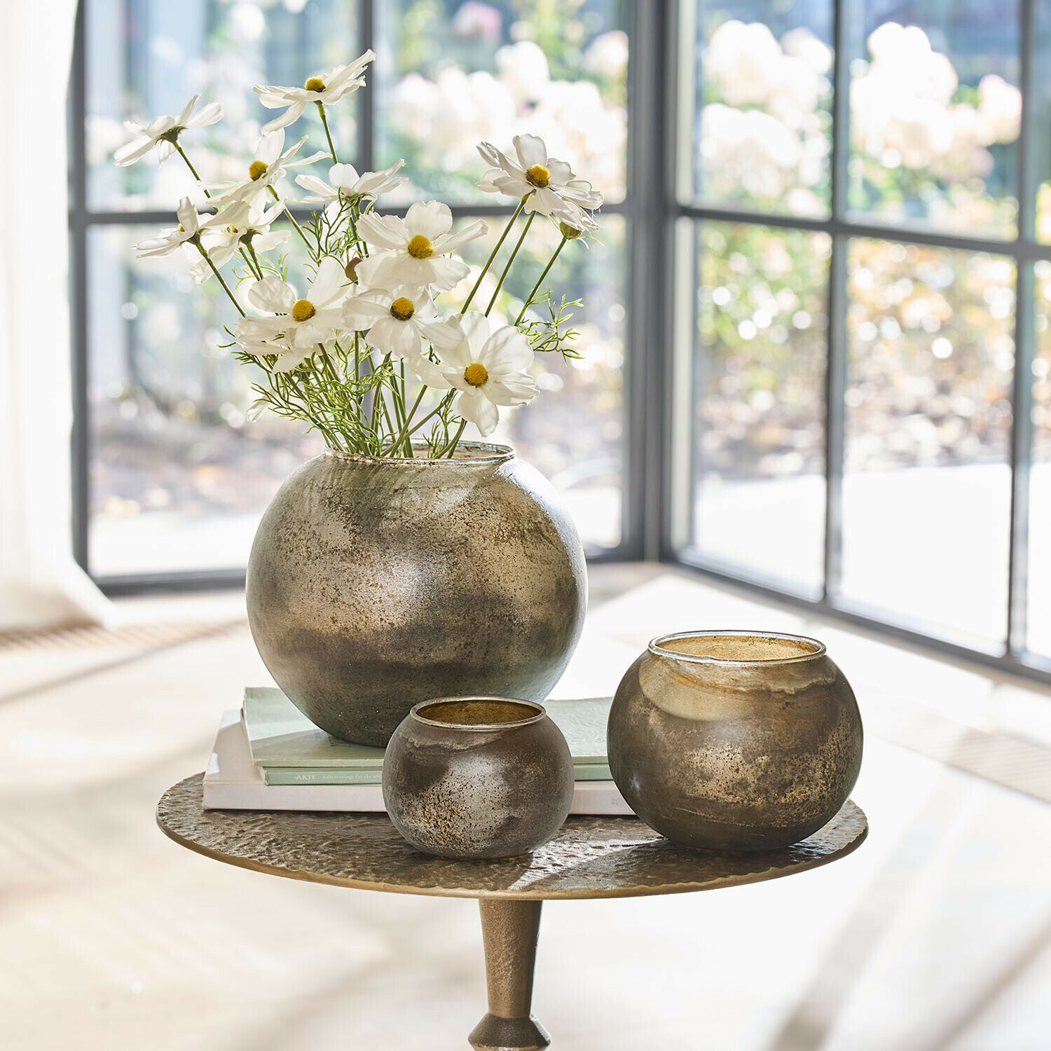 Vaas set van 3 Orvellas Set van drie ronde glazen vazen in antiek goud op tafel met bloemen en boeken