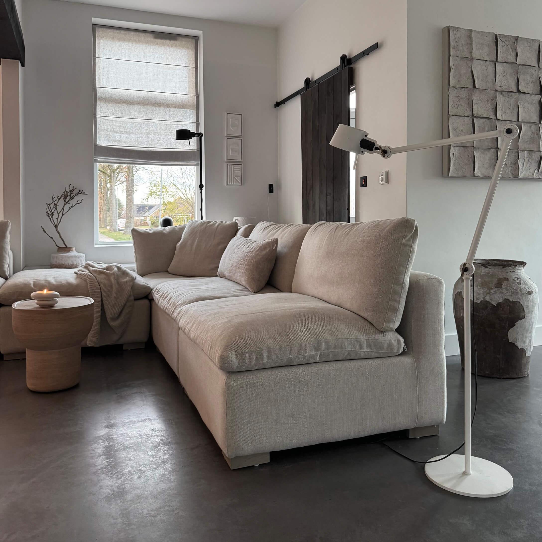 Beige stoffen hoekbank in moderne woonkamer met staande lamp en houten bijzettafel