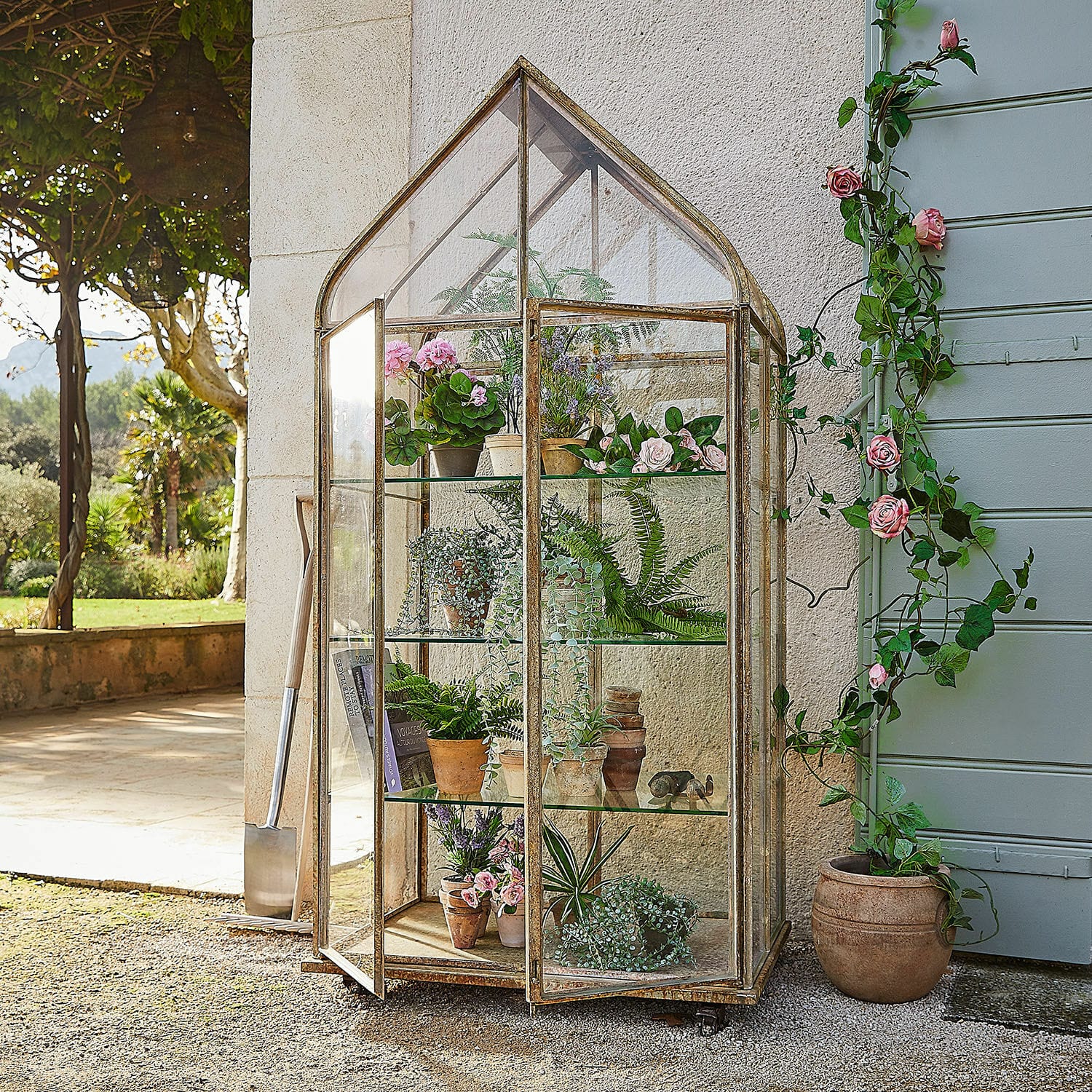 Serre Belfaux Serre de jardin vintage en métal et verre avec plantes en pot et fleurs décoratives.
