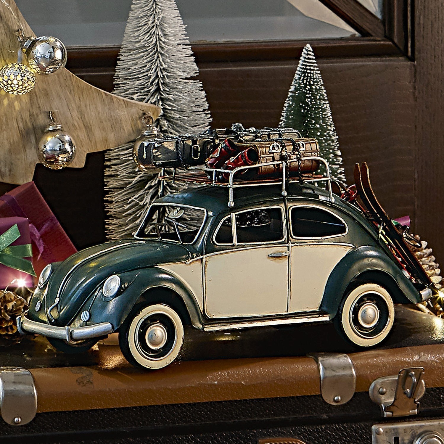 Model van groen-crèmekleurige auto met metalen bagagerek en ski's tegen kerstdecoratie