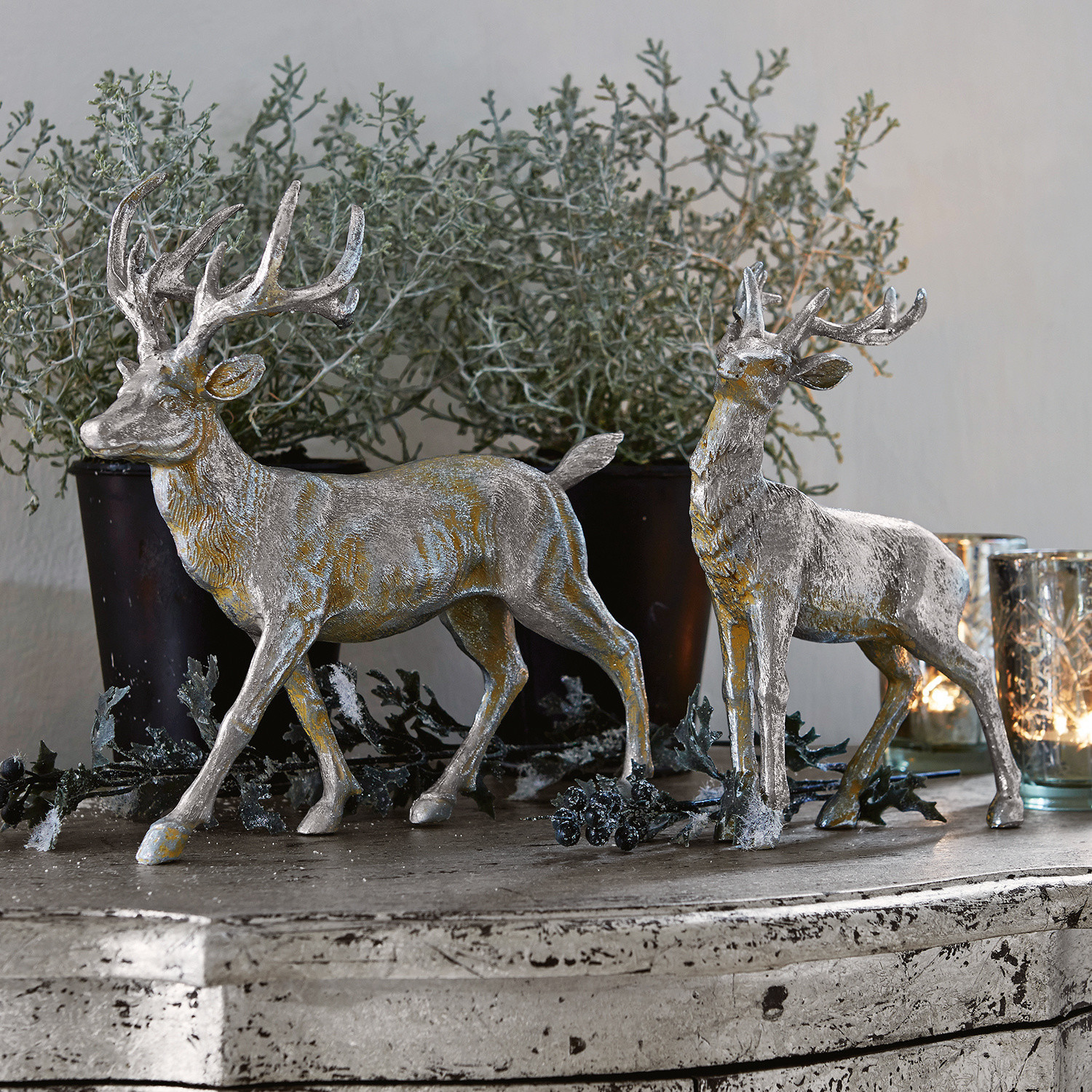 Hert set van 2 Rudy & Son Twee zilveren hertendecoraties van kunststof op rustiek dressoir met planten en kaarsen