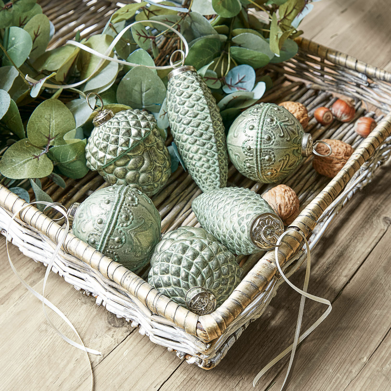 Lot de 6 décorations de Noël Quirat Décorations de Noël vertes en forme de pommes de pin et glands dans un panier en osier sur une table en bois