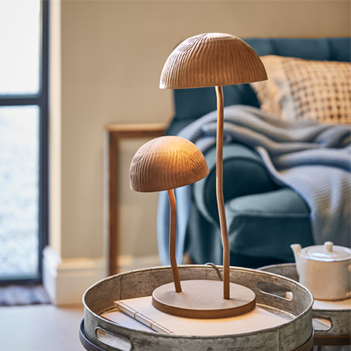 Lampe de table en bois forme champignon couleur naturelle posée sur un plateau en métal dans un salon