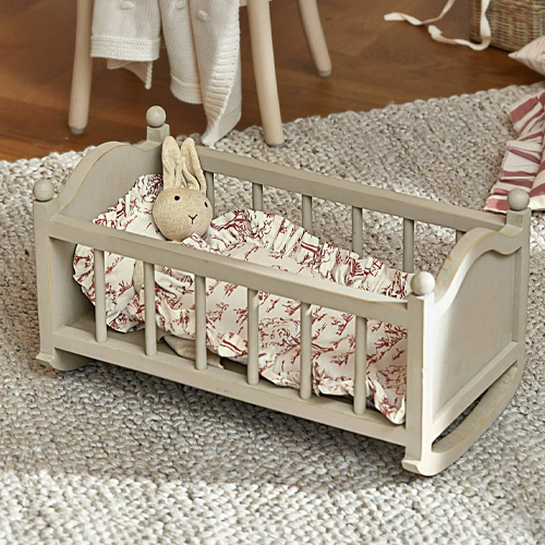Berceau en bois gris pour poupée avec lapin en peluche et literie à motifs sur tapis