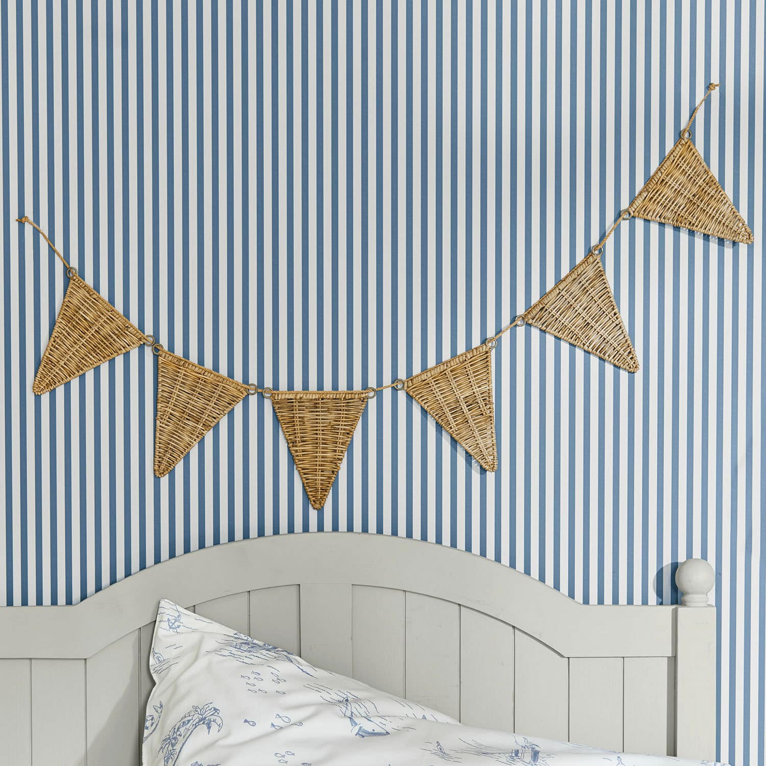 Vlaggenlijn Anglemont Decoratieve slinger van gevlochten riet in driehoekige vorm aan blauw-wit gestreepte muur in slaapkamer