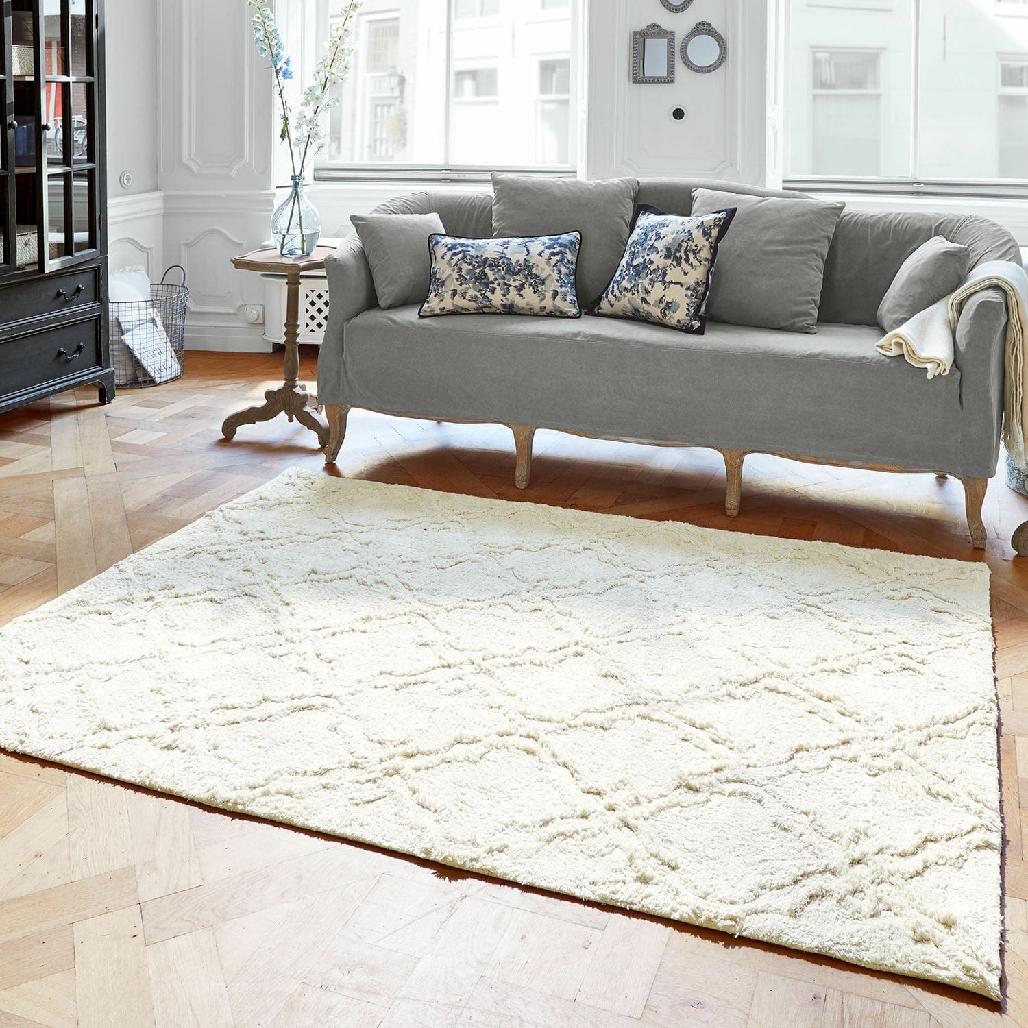 Tapis Petrus Tapis crème clair à motif doux sur parquet en bois dans un salon avec canapé gris