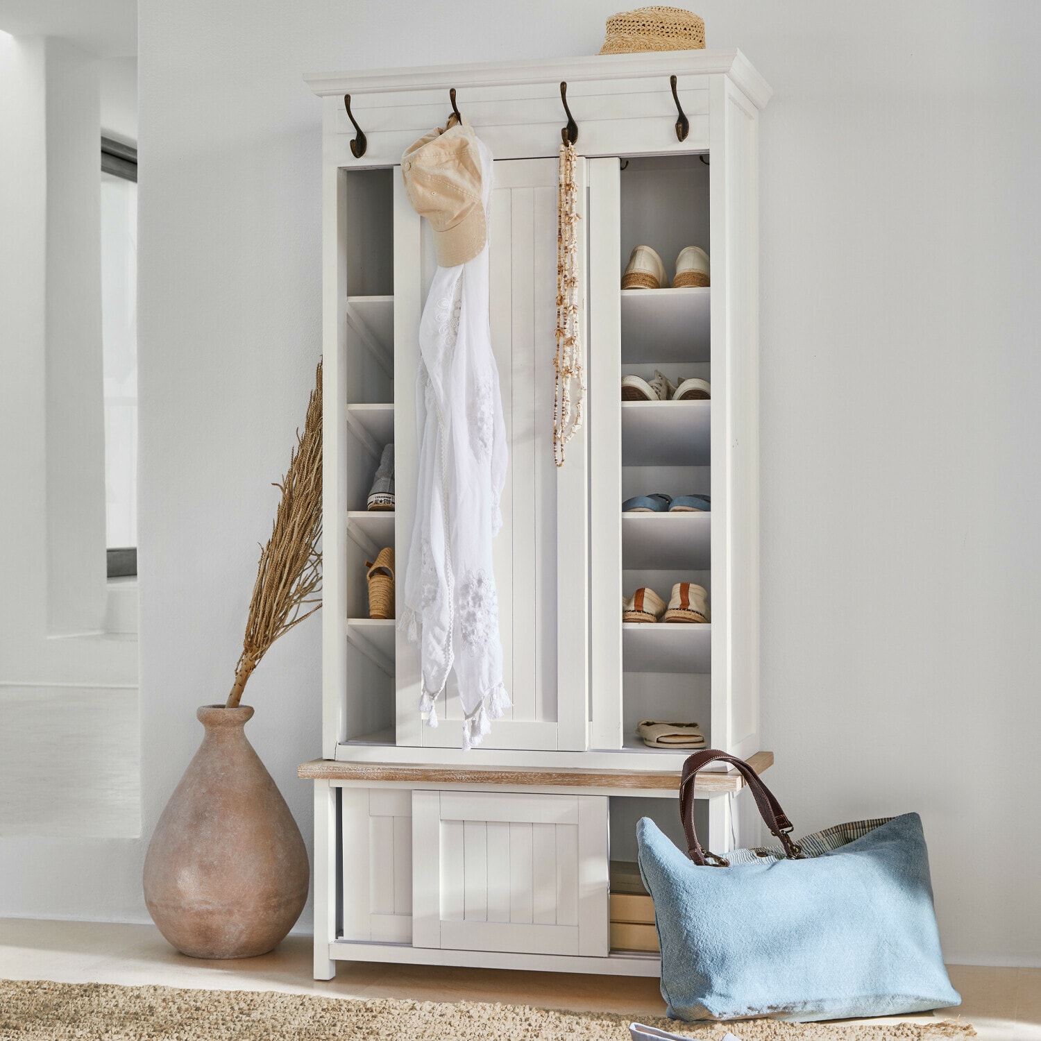 Garderobekast Remerton Witte houten schoenenkast met haken en planken, blauwe tas en strohoed als decoratie