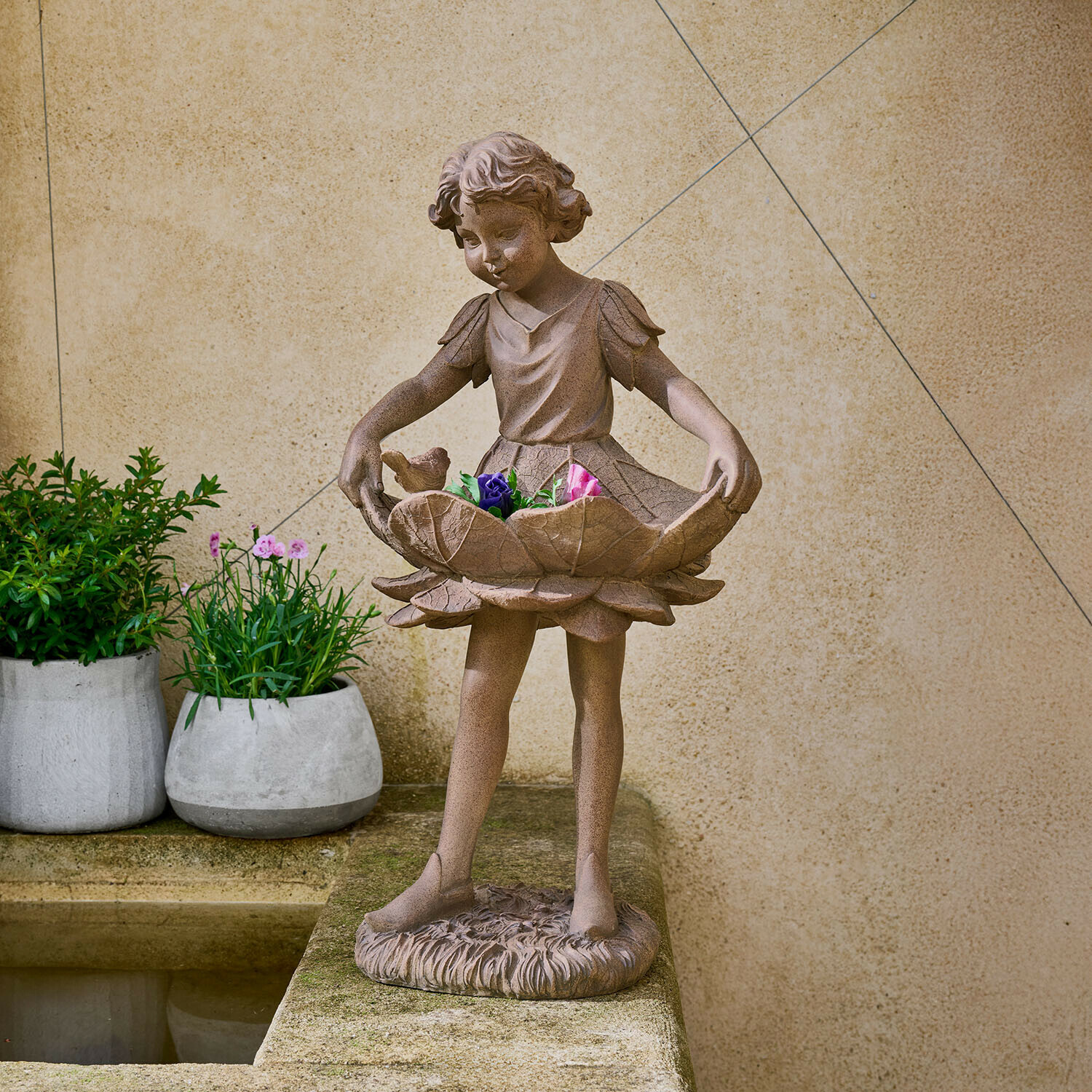 Figurine décorative Aimorise Statue en pierre brune d'une fillette tenant un bol en forme de fleur avec des fleurs colorées dans un jardin