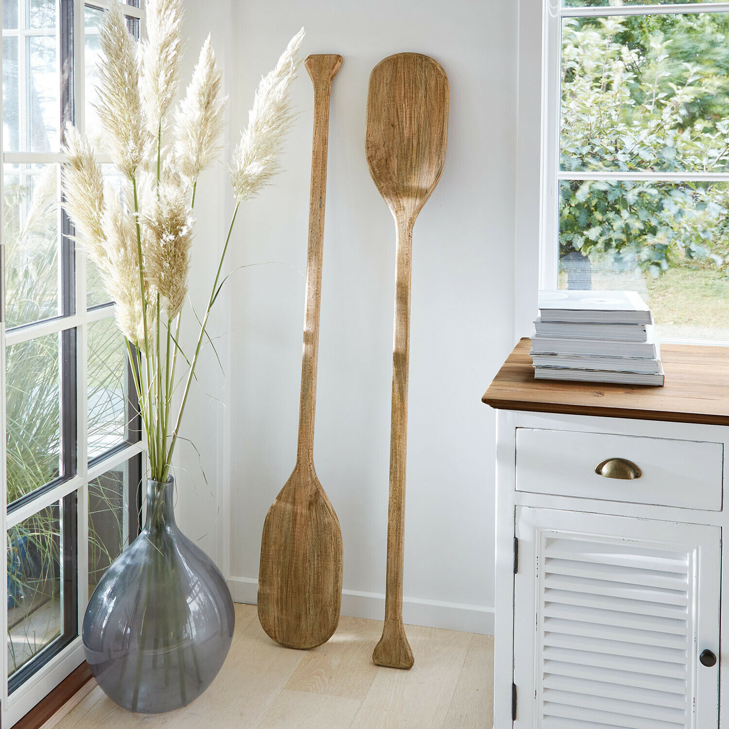 Decoratieve peddel set van 2 Windermount Twee decoratieve houten peddels in lichte kamer naast grijze vaas en witte kast