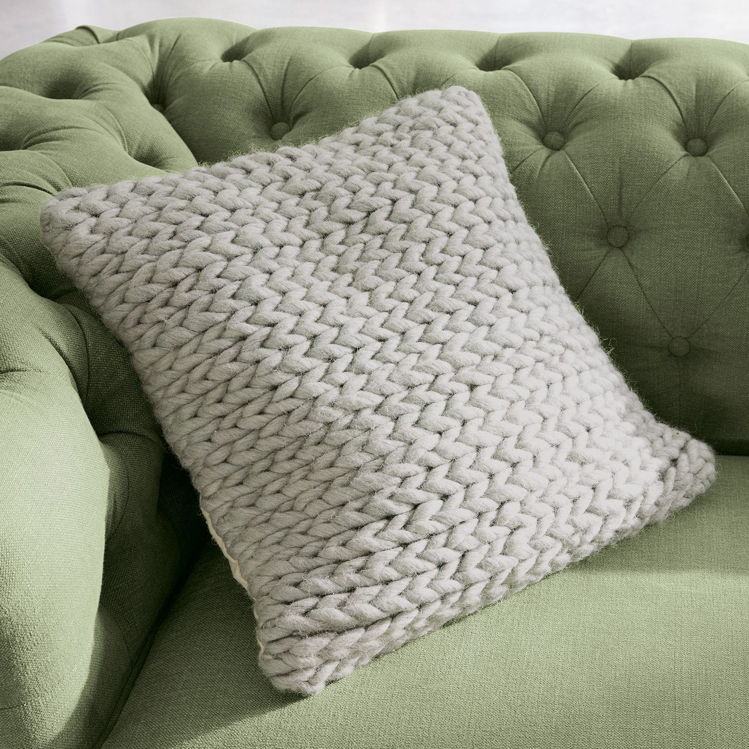 Kussenhoes Limnia Beige kussen met grove brei van zachte wol op groene gestoffeerde bank