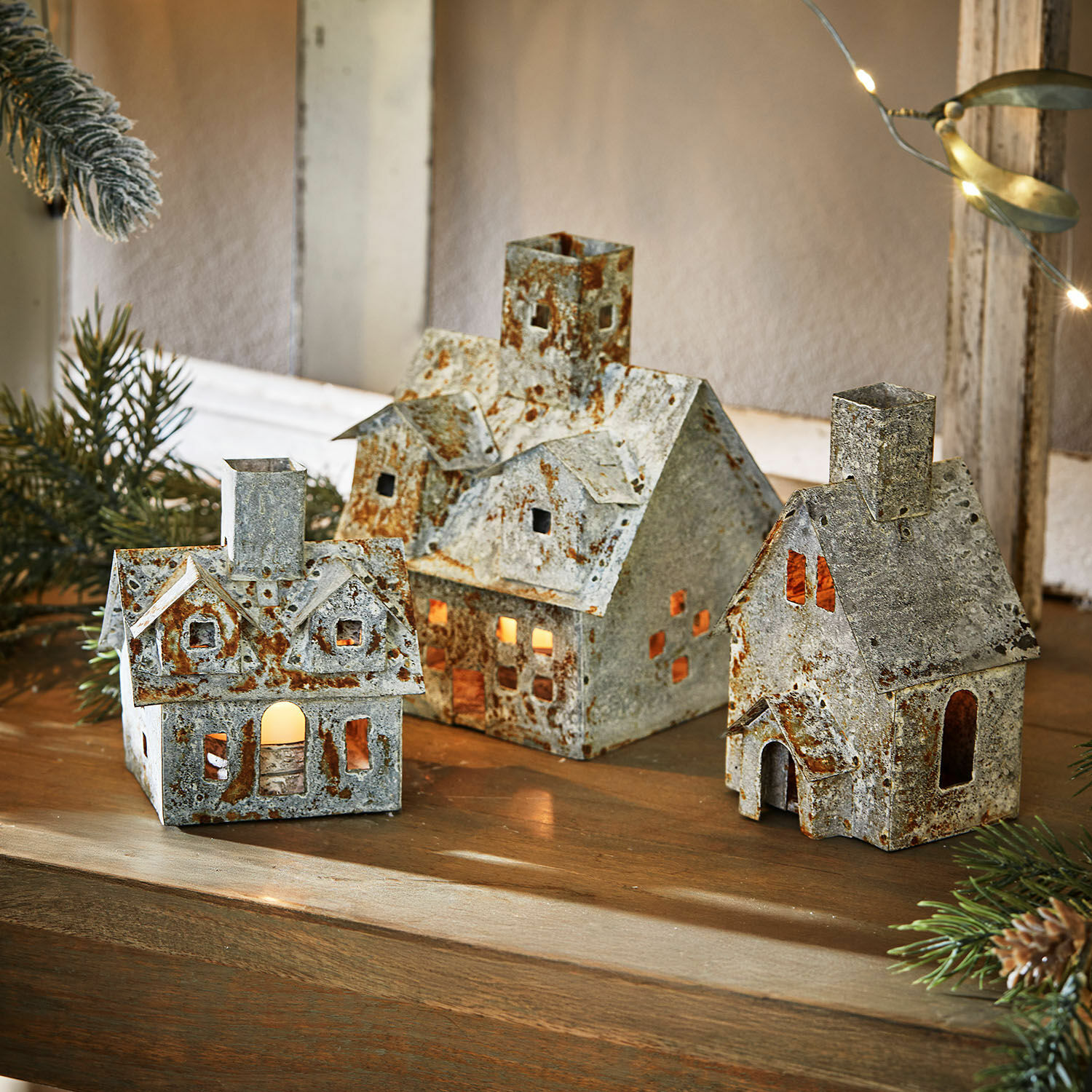 Windlicht set van 3 Granstad Set van drie metalen decoratieve huisjes met roestlook en binnenverlichting op houten tafel