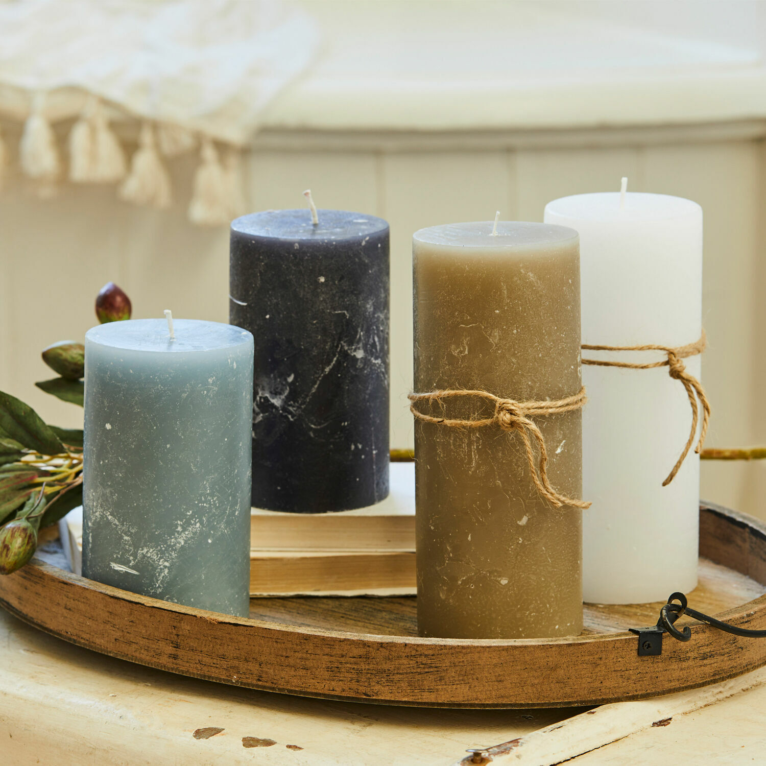 Lot de 4 bougies Berekua Ensemble de quatre bougies bleu, noir, marron et blanc sur un plateau en bois décoratif