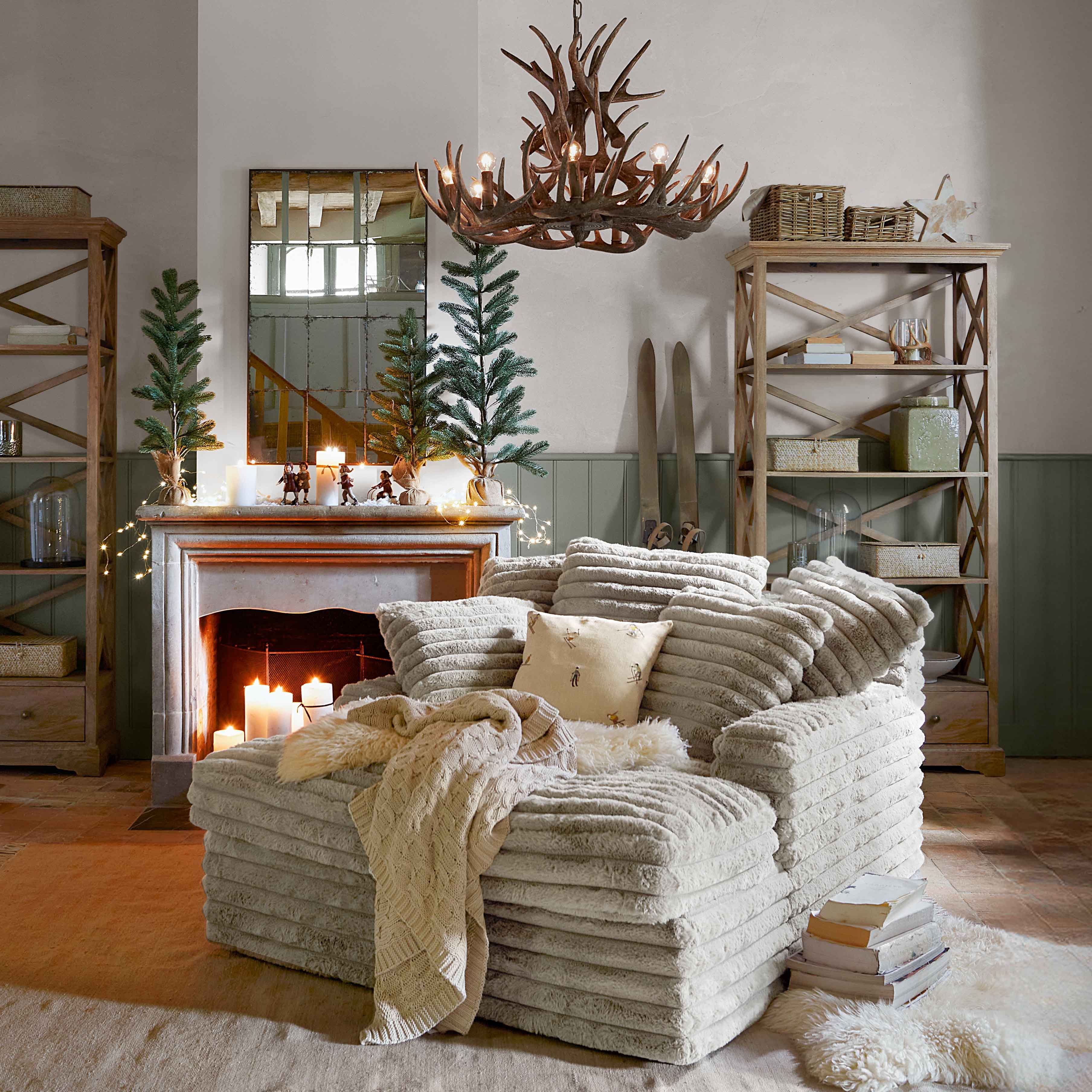 Comfortabele beige fauteuil van zachte stof met deken en kussen in rustieke woonkamer met open haard