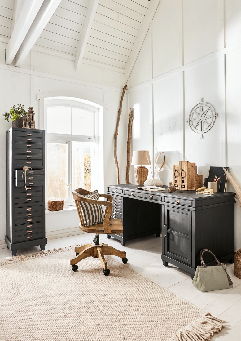 Bureau en bois noir et armoire haute à tiroirs dans une pièce lumineuse et chaleureuse pour travailler