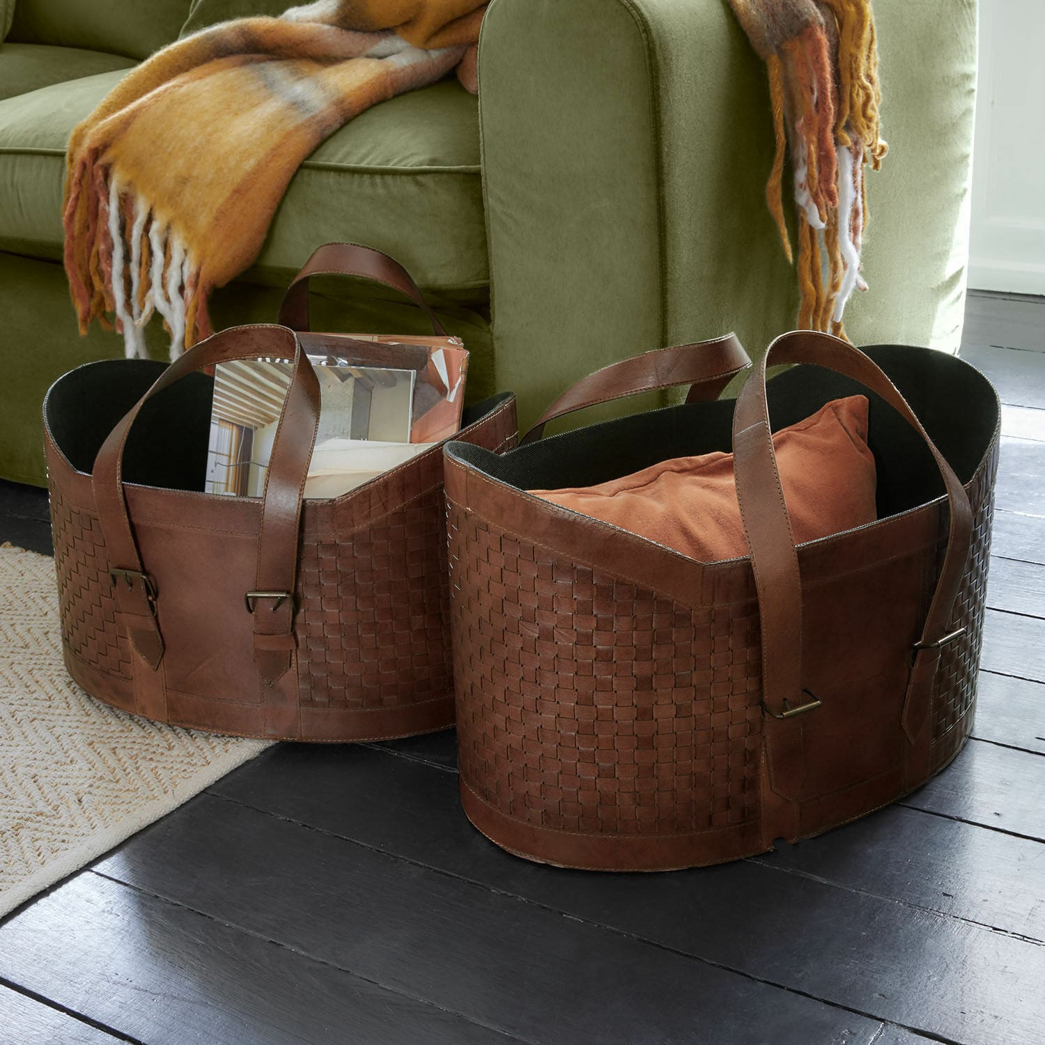 Set de 2 corbeilles Tavari Paniers en cuir marron tressé pour rangement au sol près d'un canapé vert olive