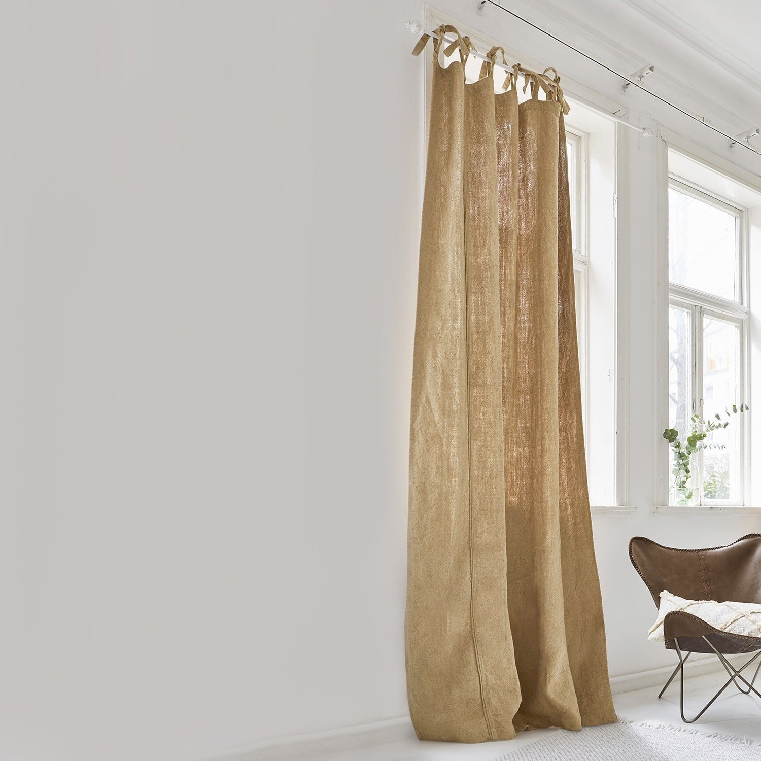 Gordijn Uma Beige gordijn van natuurlijk linnen in lichte kamer met groot raam en bruine stoel