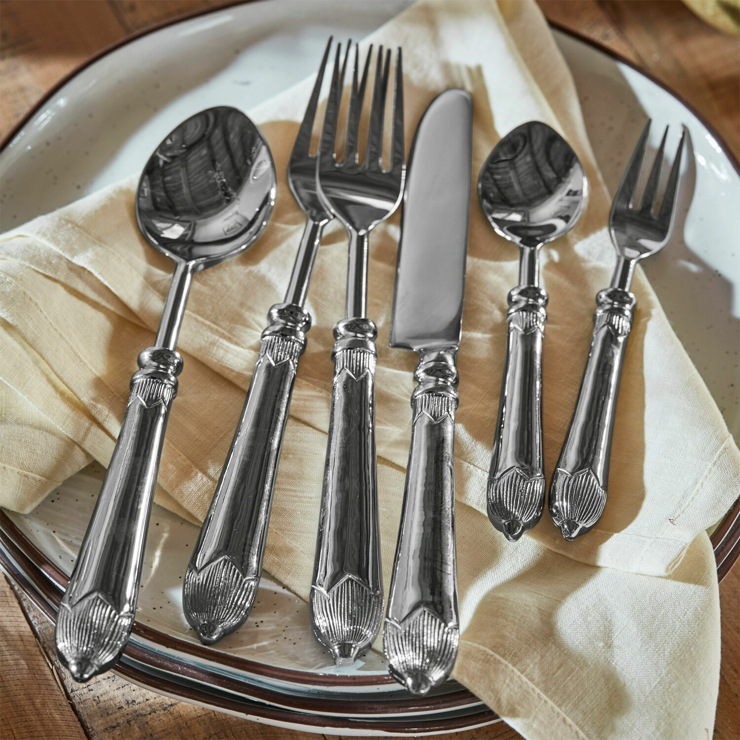 Bestek Gasharba Set zilverkleurig roestvrijstalen bestek op crèmekleurige servet op bord, elegante keukenaccessoires