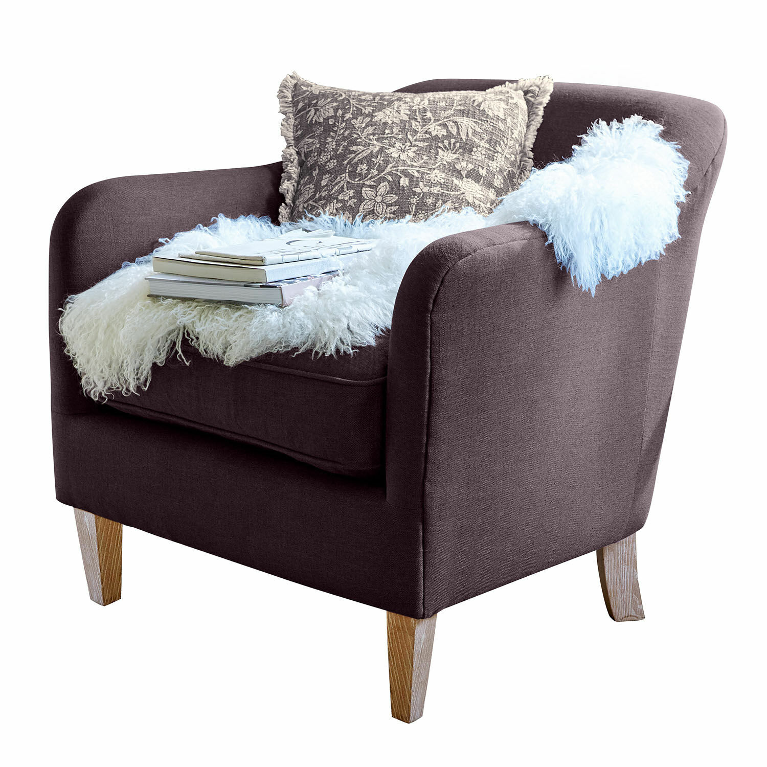 Fauteuil Jefferson Donkerbruine gestoffeerde fauteuil met houten poten, versierd met kussen en witte bontachtige deken