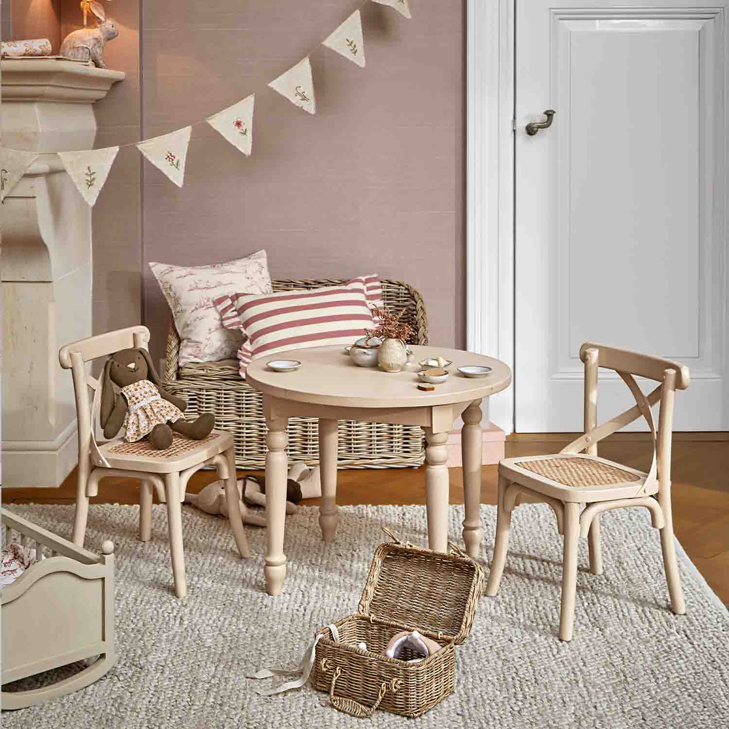 Table ronde en bois clair avec deux chaises à assise tressée dans une chambre d'enfant cosy