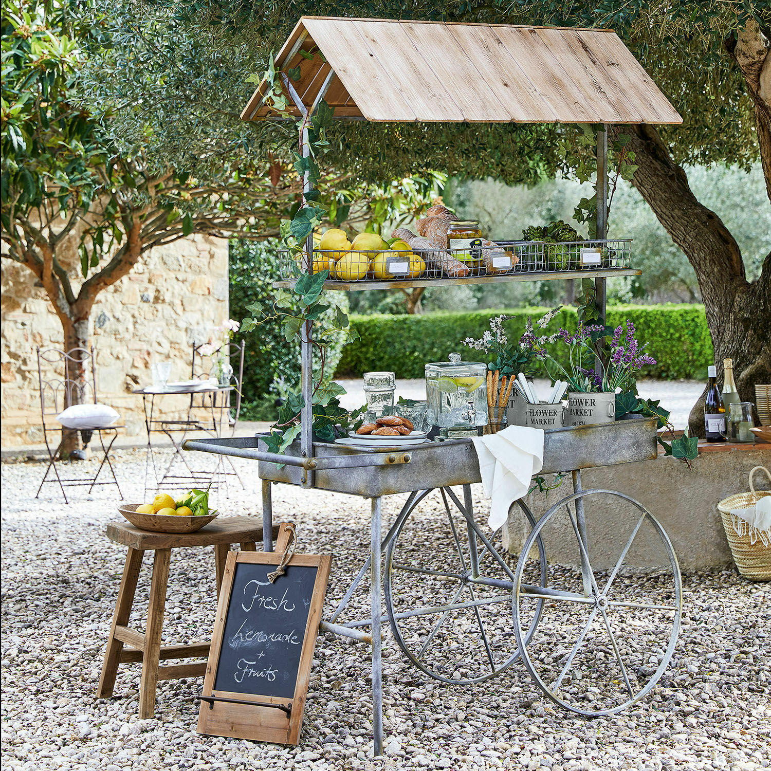 Table de rempotage Granby Chariot en métal avec toit en bois, fruits frais et limonade dans un jardin ensoleillé