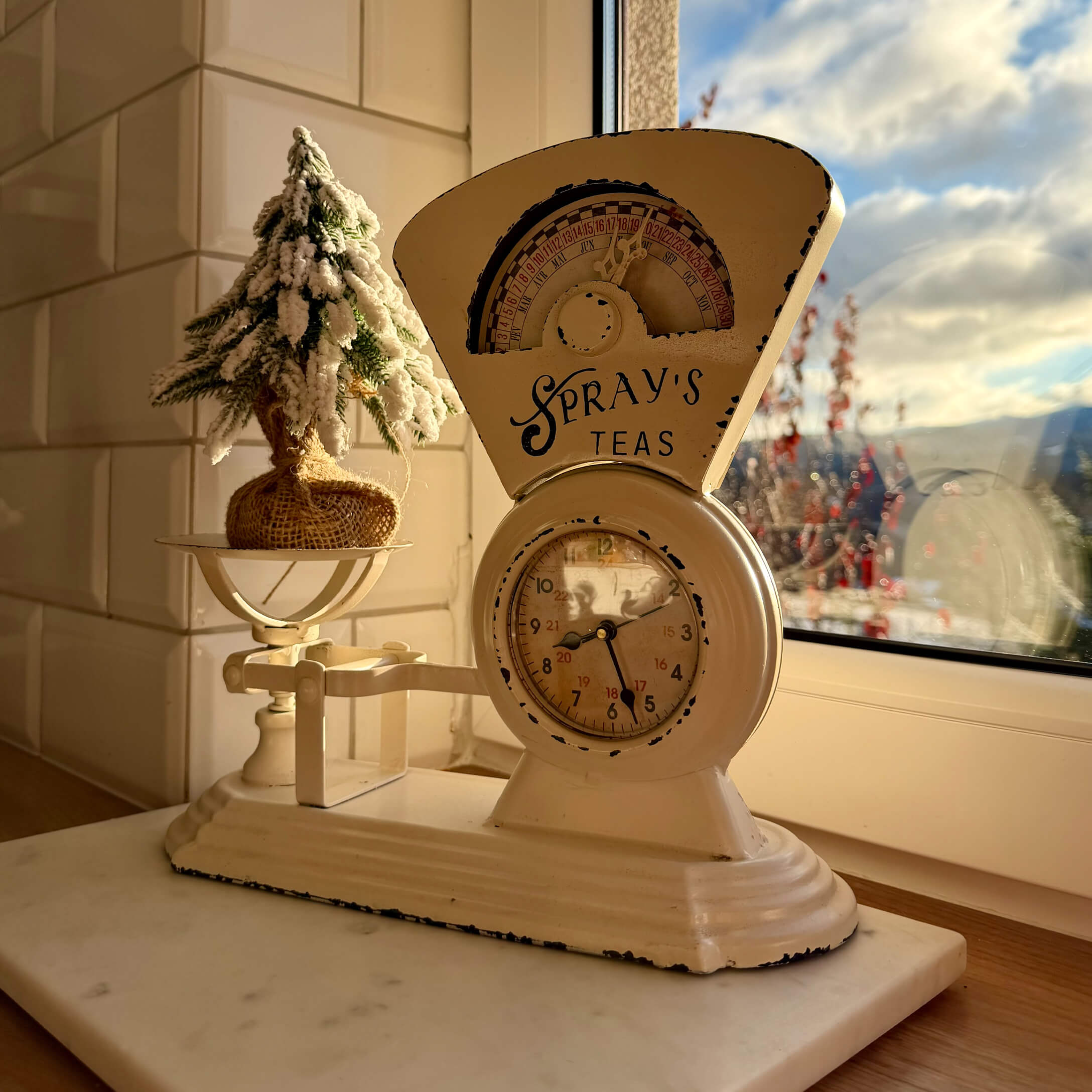 Balance de cuisine en métal beige avec horloge et décoration de Noël sur le rebord de la fenêtre