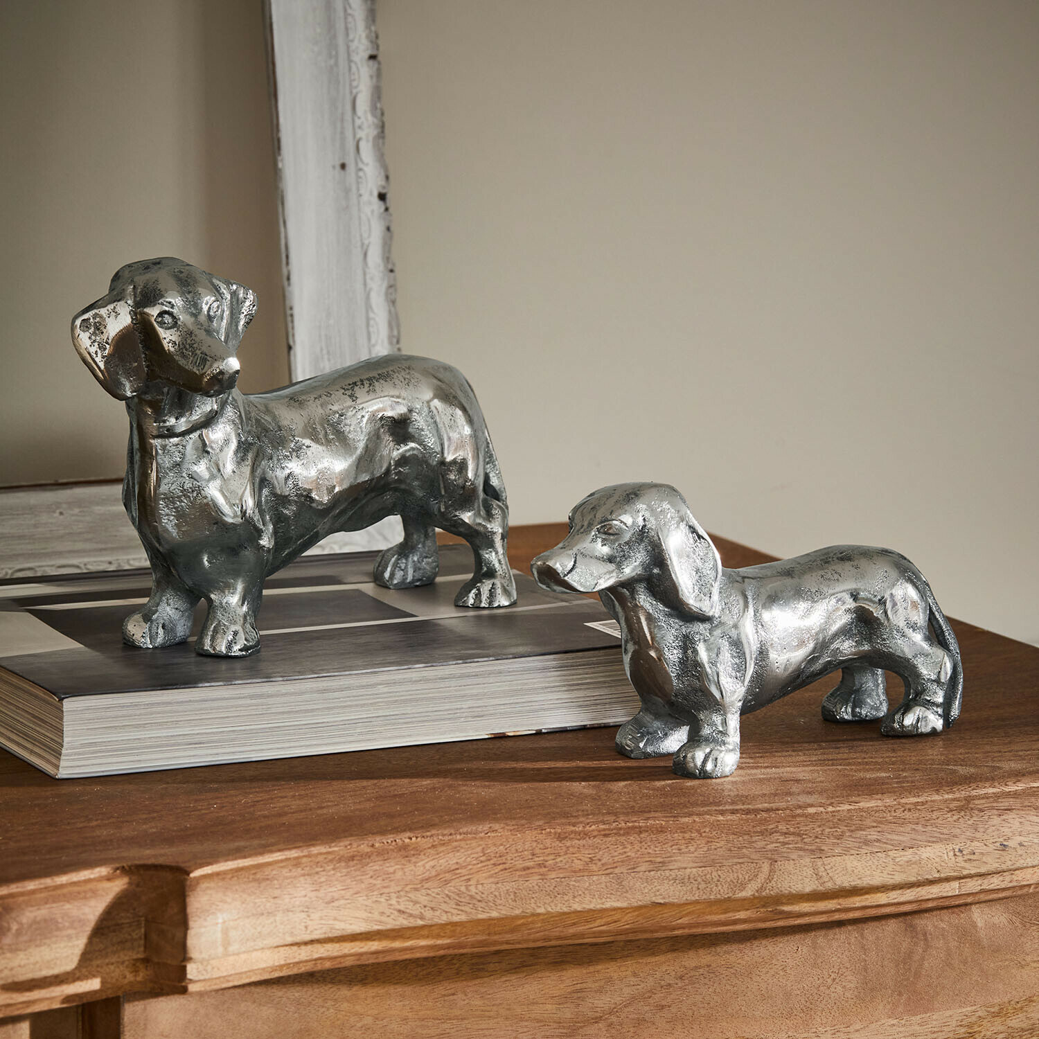 Lot de 2 chiens décoratifs Calwen Deux figurines de teckels en métal argenté posées sur une table en bois, décoration intérieure élégante
