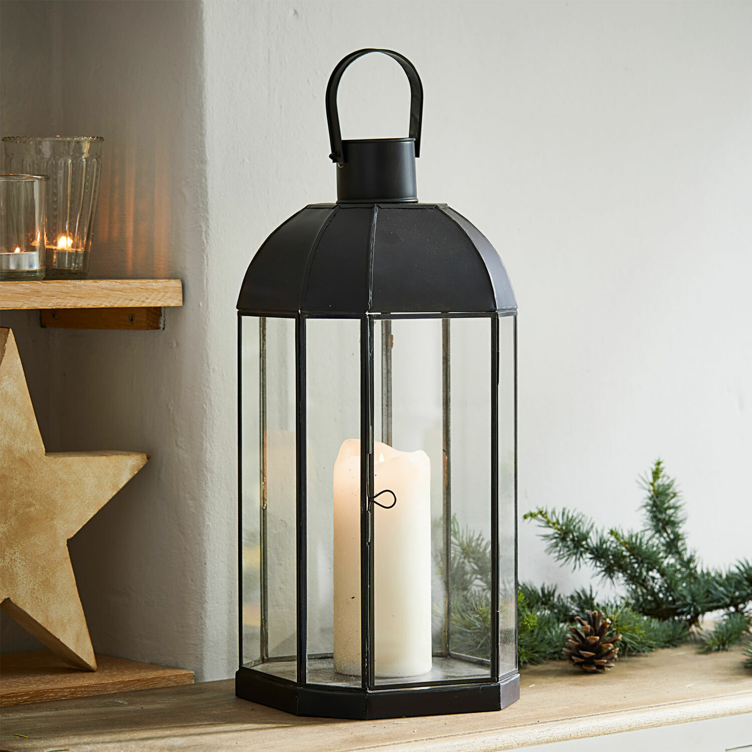 Lantaarn Comines Zwarte metalen lantaarn met helder glas en witte kaars op houten tafel met kerstdecoratie