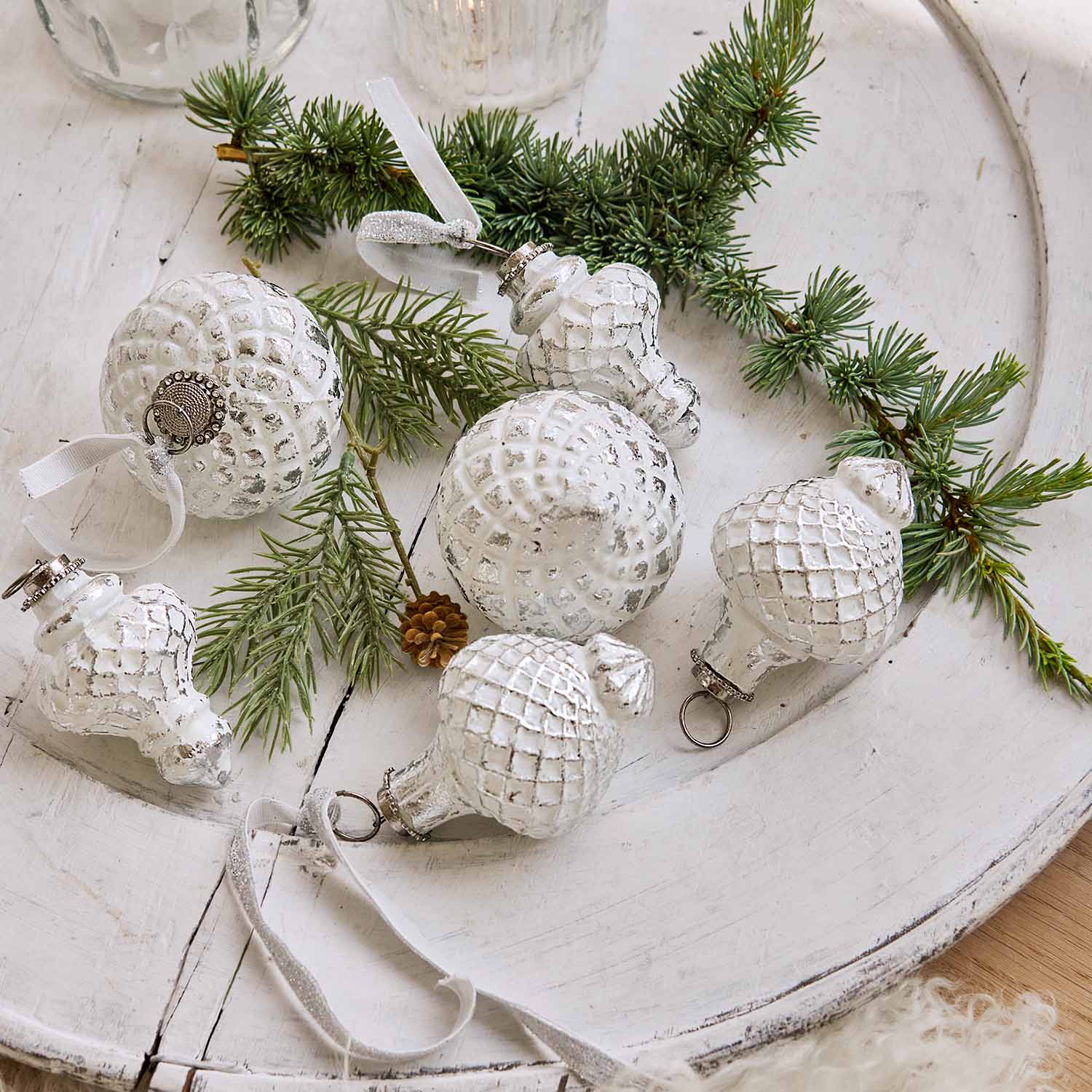 Witte kerstballen met ruitpatroon op houten dienblad met dennentakken, feestelijke decoratie