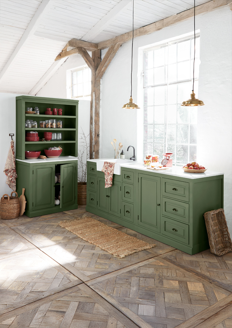 Cuisine en bois vert avec plan de travail blanc et suspensions en laiton dans un intérieur rustique lumineux