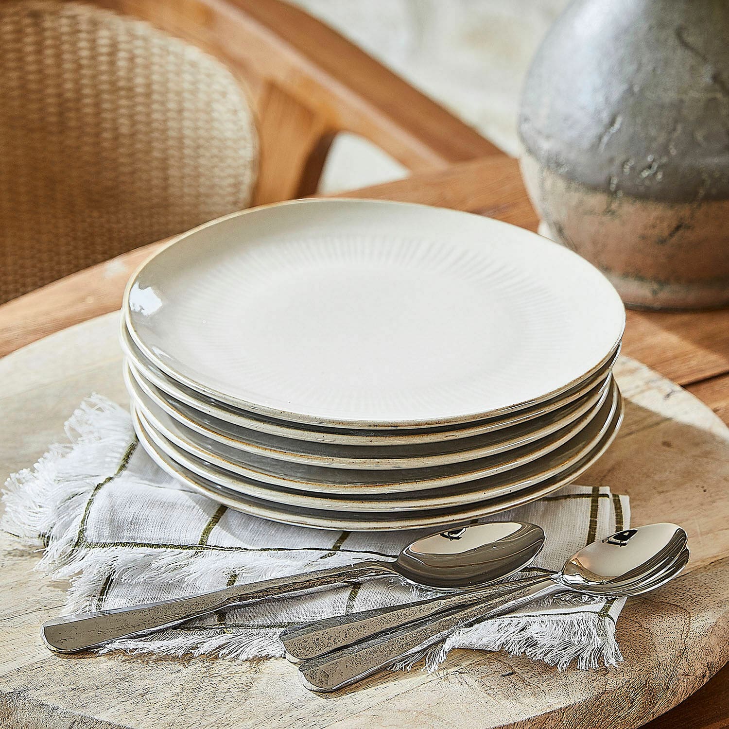 Dessertbordje set van 6 Périers Set van zes crèmekleurige keramische borden met subtiel patroon en metalen lepels op linnen servet