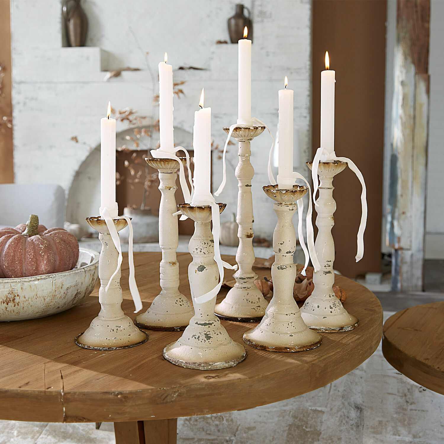 Kandelaar set van 6 Rivondelle Set van zeven crèmekleurige metalen kandelaars met witte kaarsen op houten tafel, interieurdecoratie
