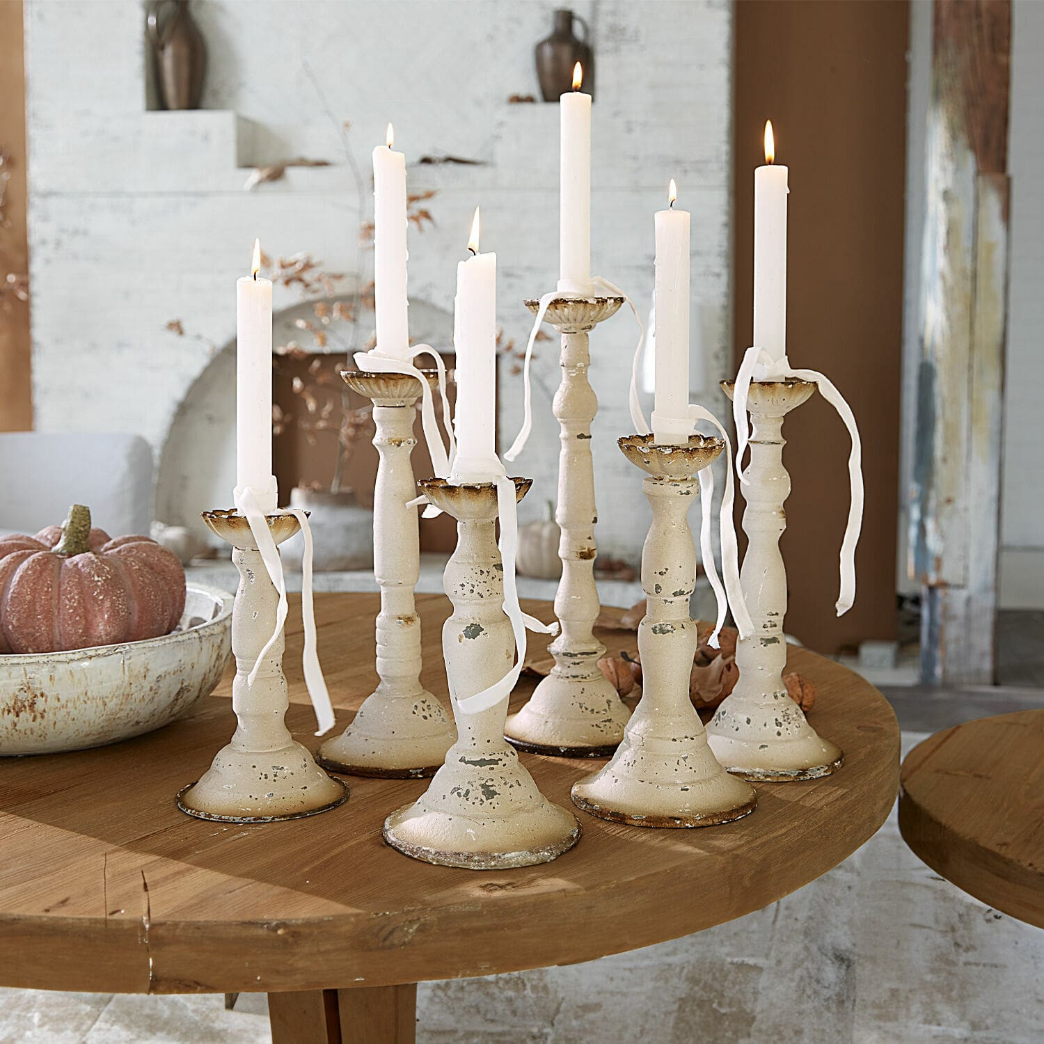 Lot de 6 bougeoirs Rivondelle Ensemble de sept bougeoirs en métal crème avec bougies blanches sur une table en bois, décoration intérieure