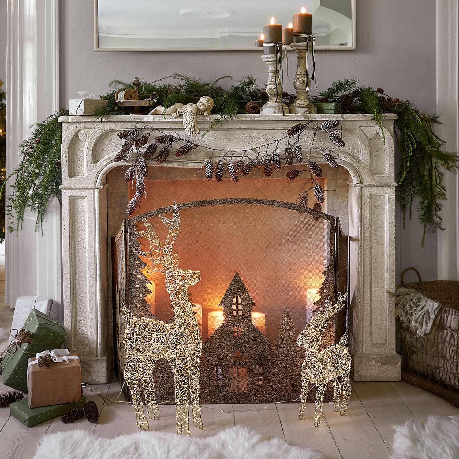 Console de cheminée Woodcroft Cheminée décorative en pierre blanche avec rennes lumineux et bougies de Noël dans un salon cosy