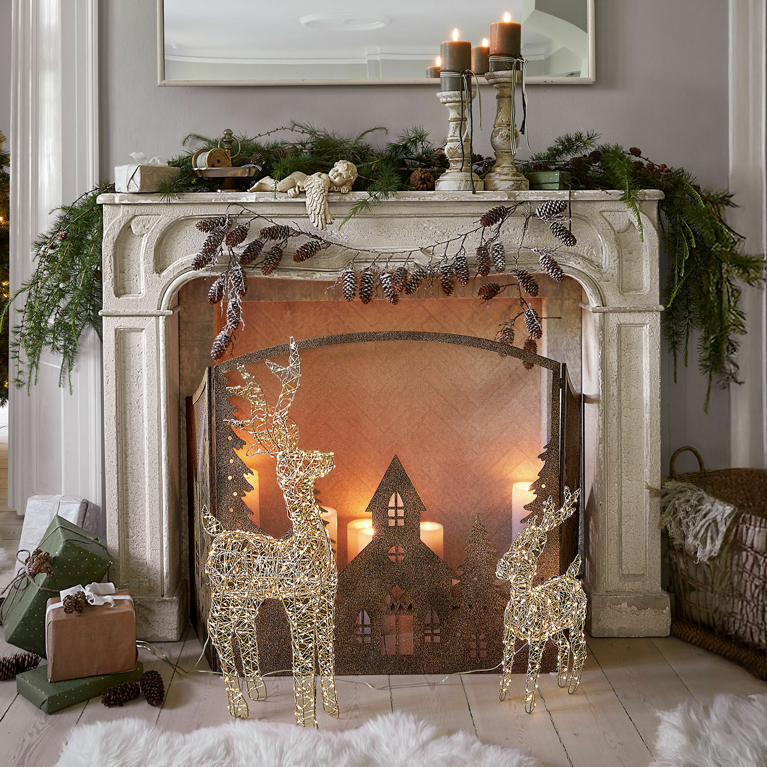 Console de cheminée Woodcroft Cheminée décorative en pierre blanche avec rennes lumineux et bougies de Noël dans un salon cosy