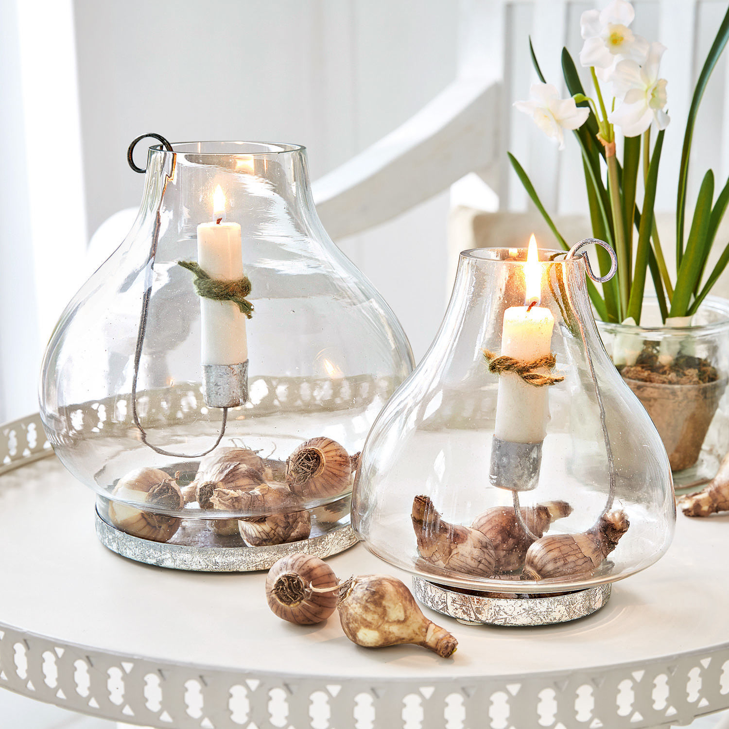 Lot de 2 photophores Vallereuil Lanterne en verre avec bougies blanches et bulbes de fleurs sur une table en métal blanc décorative