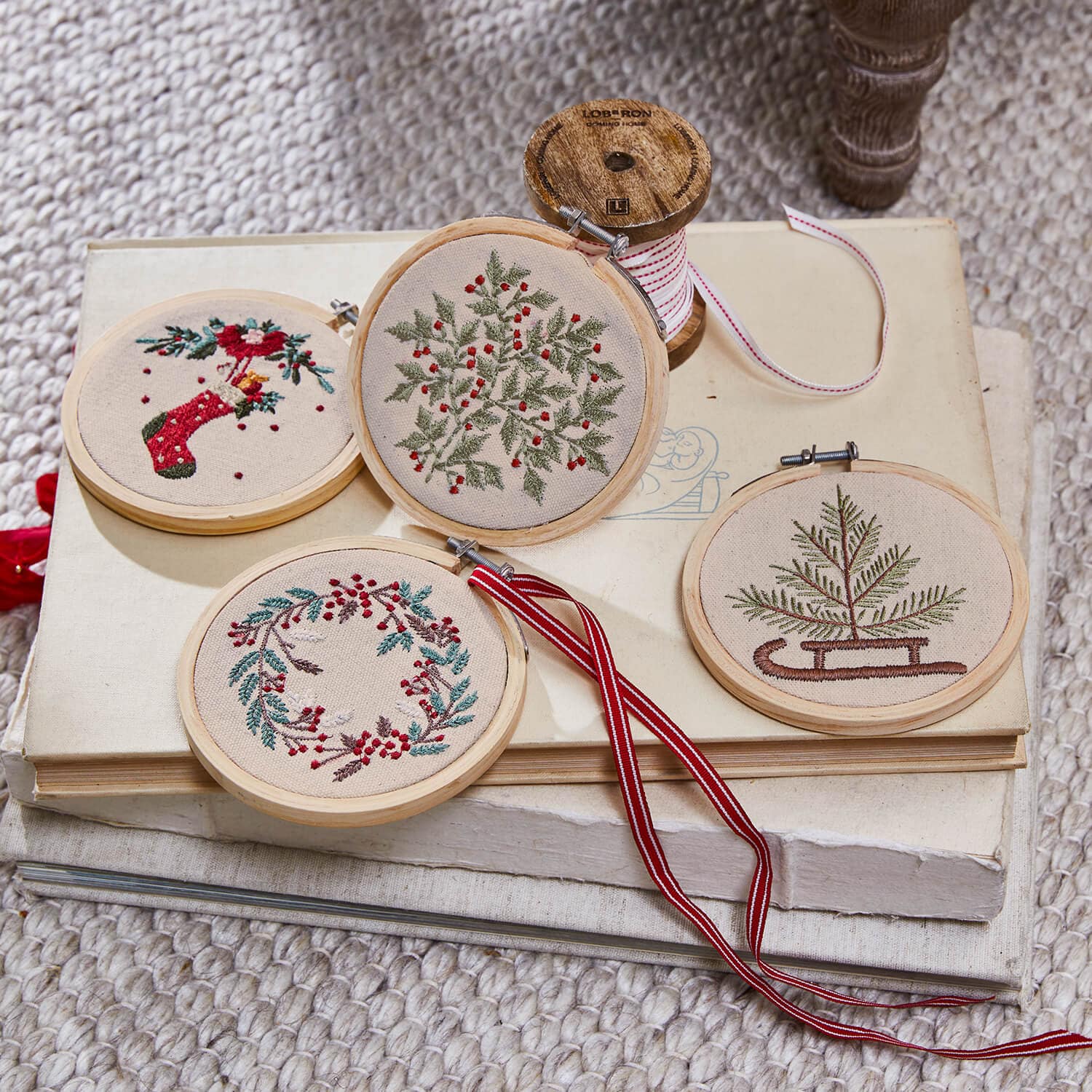 Ensemble de quatre décorations brodées de motifs végétaux avec accents rouges sur fond beige