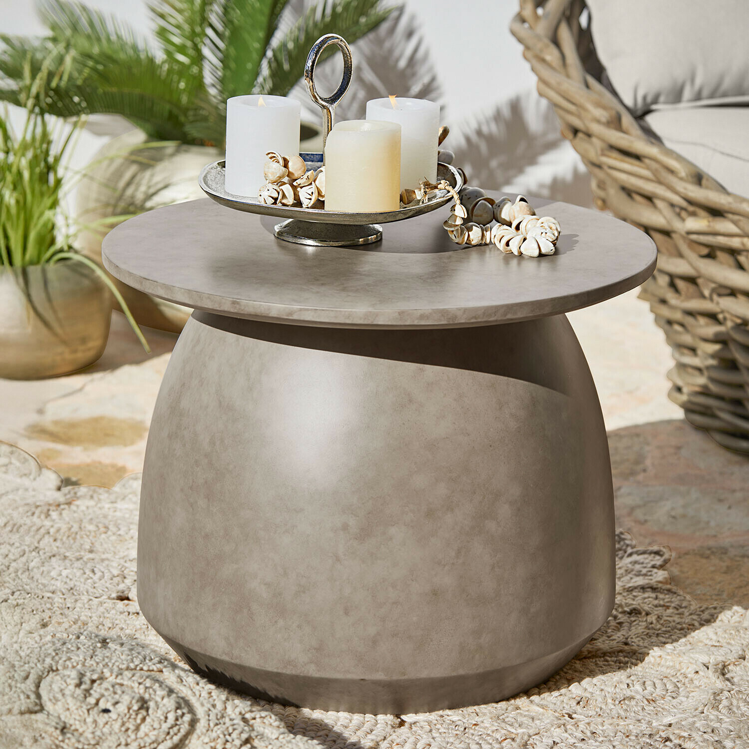 Table d’appoint Thyraen Table basse ronde en béton gris avec bougies et décorations coquillages sur terrasse extérieure