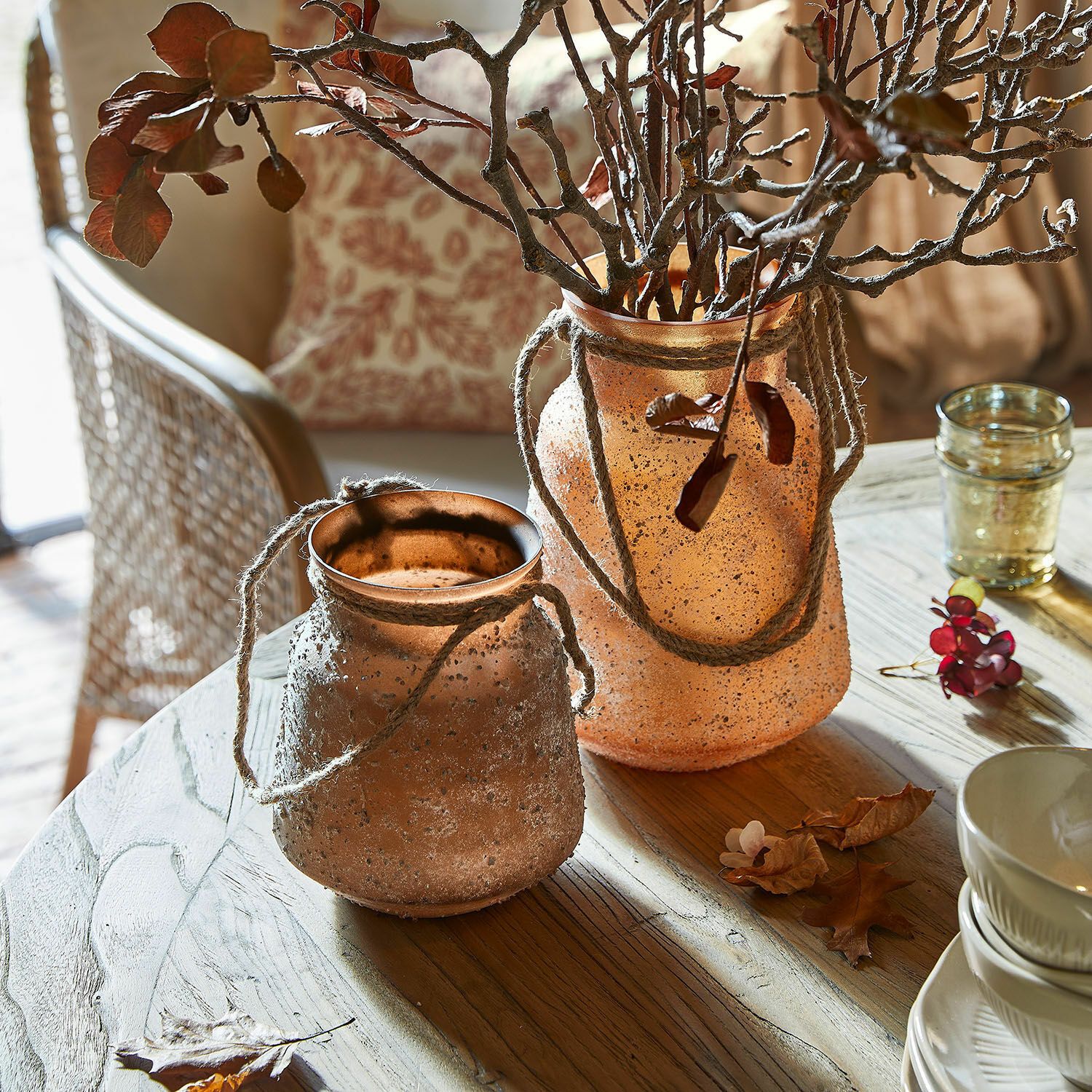 Vaas set van 2 Querello Twee decoratieve vazen van mat oranje glas met touwen op een houten tafel in een lichte woonkamer
