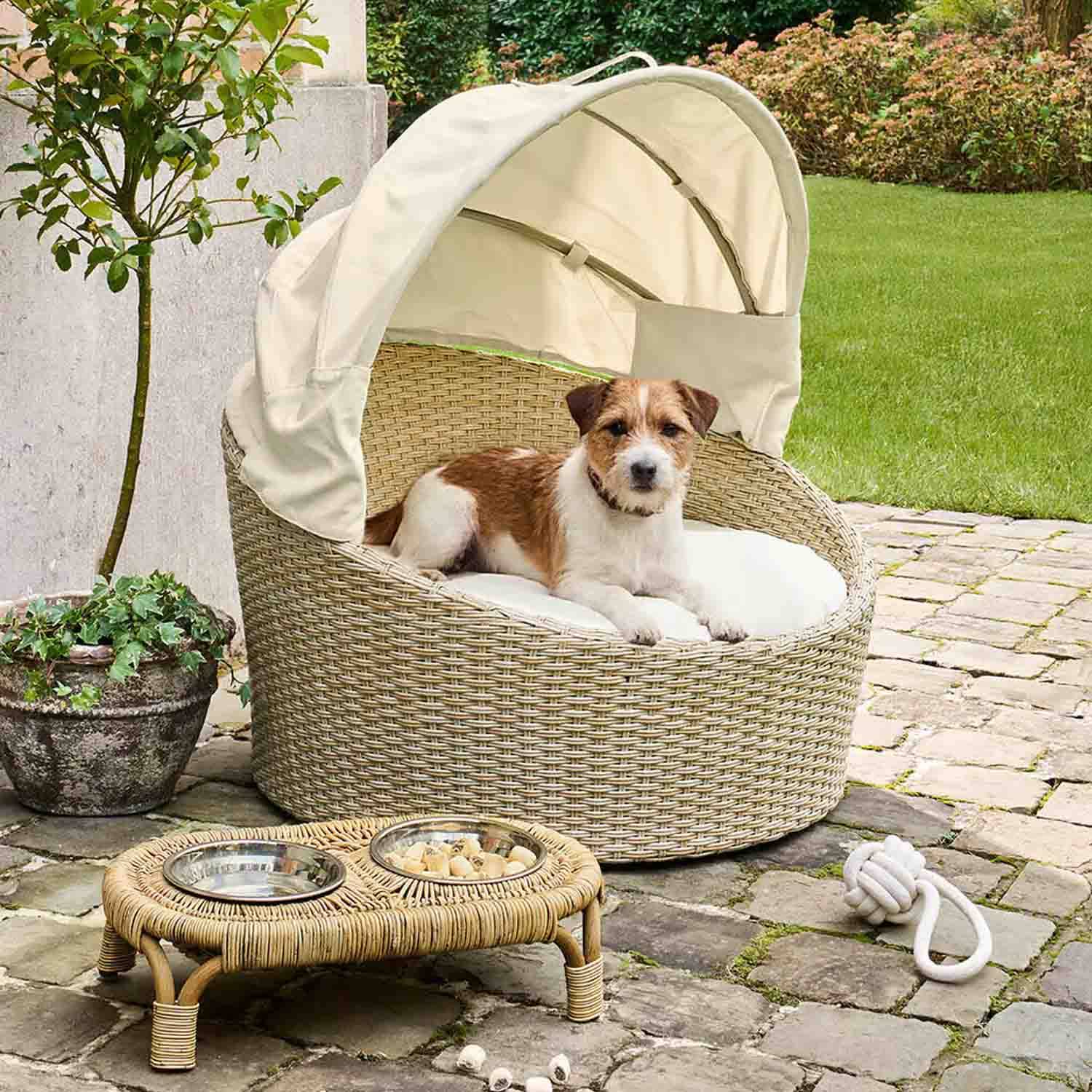 Ronde hondenmand van beige rattan met crèmekleurig dak en kussen voor buiten