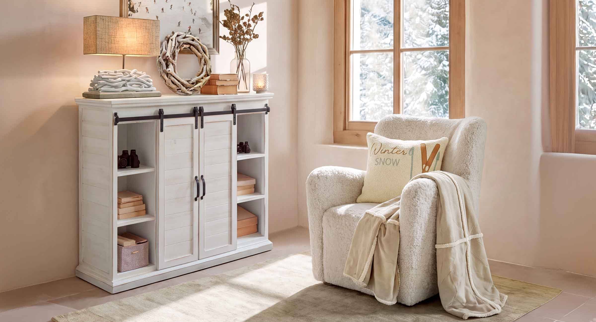 Coin cosy avec fauteuil blanc en tissu pelucheux et buffet en bois clair dans une pièce lumineuse avec vue hivernale