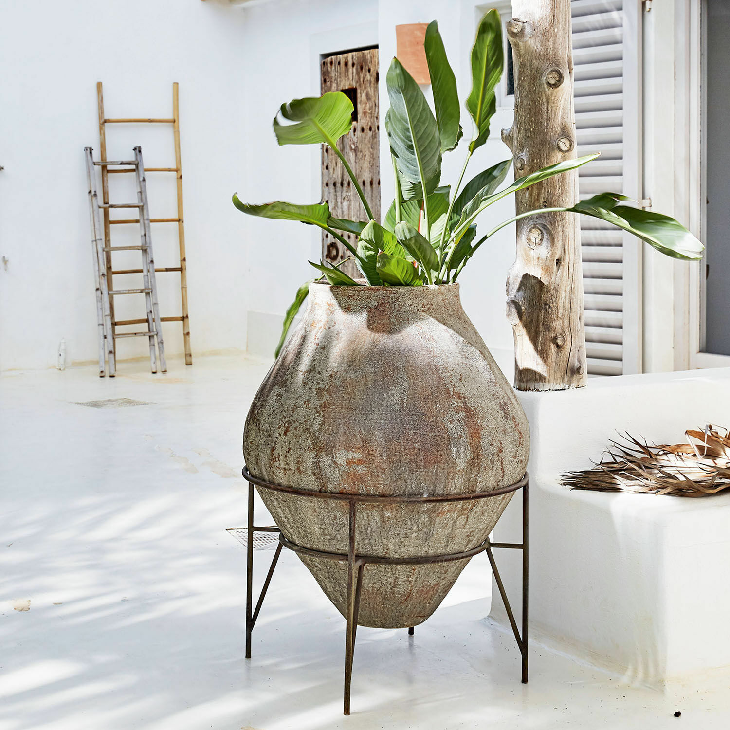Vase Pive Grand pot en pierre sur support métallique avec plante verte dans un intérieur clair et minimaliste
