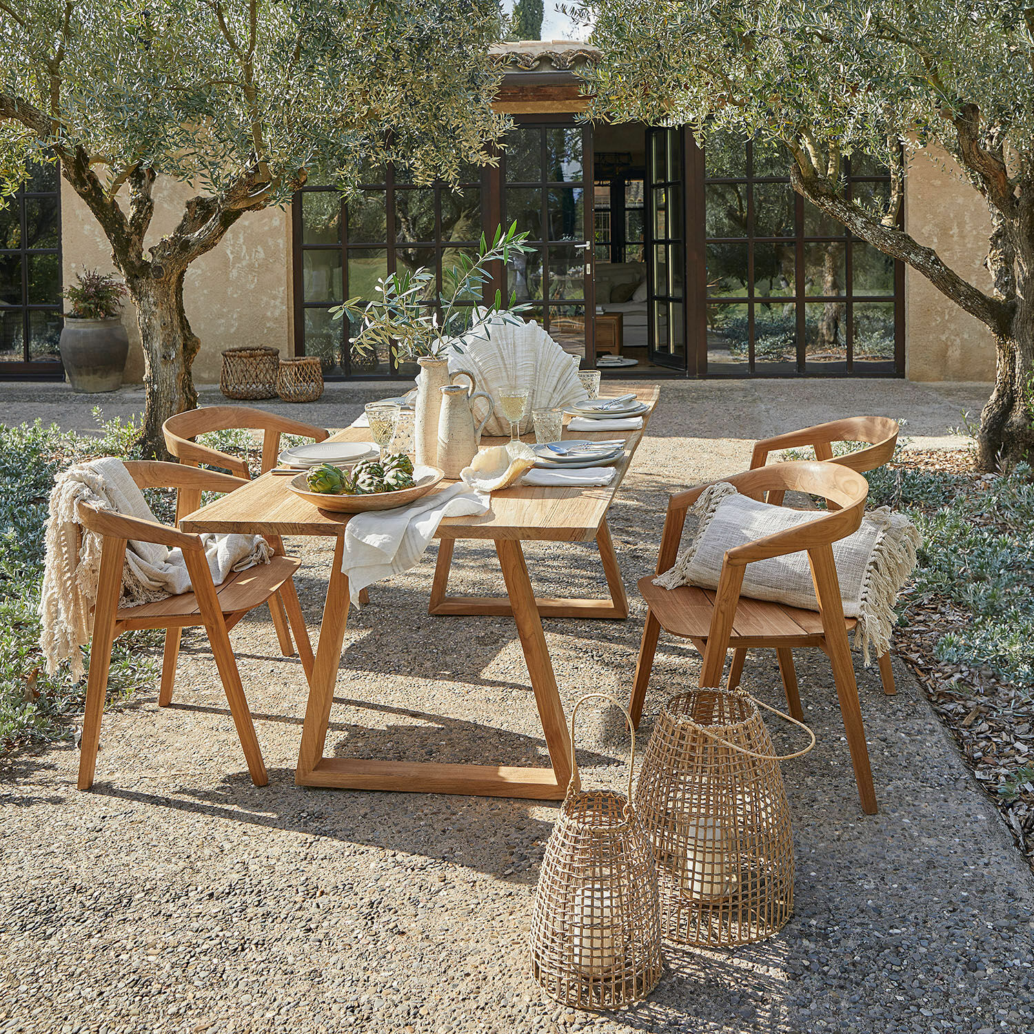 Table Saulny Ensemble de mobilier de jardin en teck naturel avec décorations et lanternes sur terrasse ensoleillée