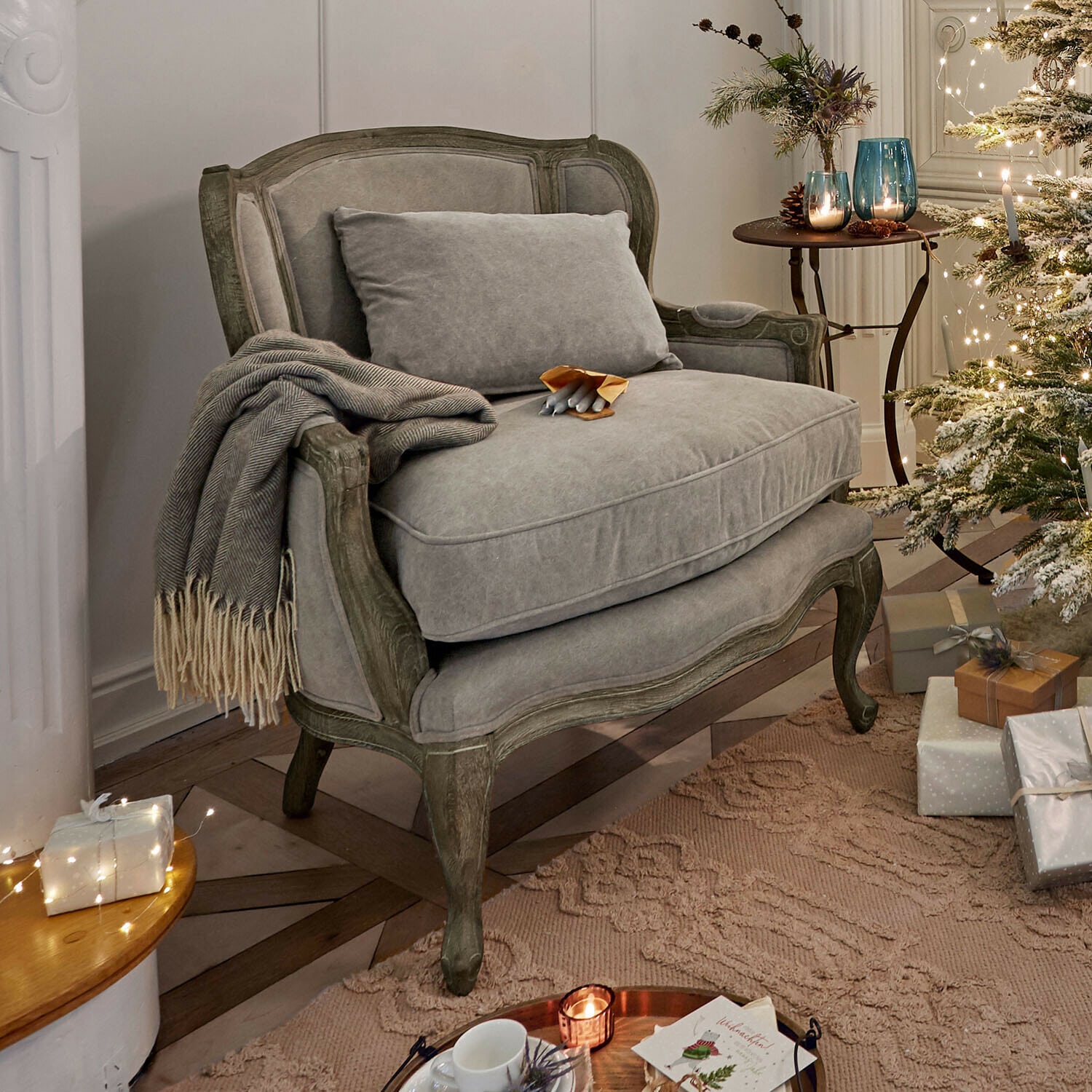 Grijze gestoffeerde bank met houten frame in gezellige kamer met kerstboom en cadeaus