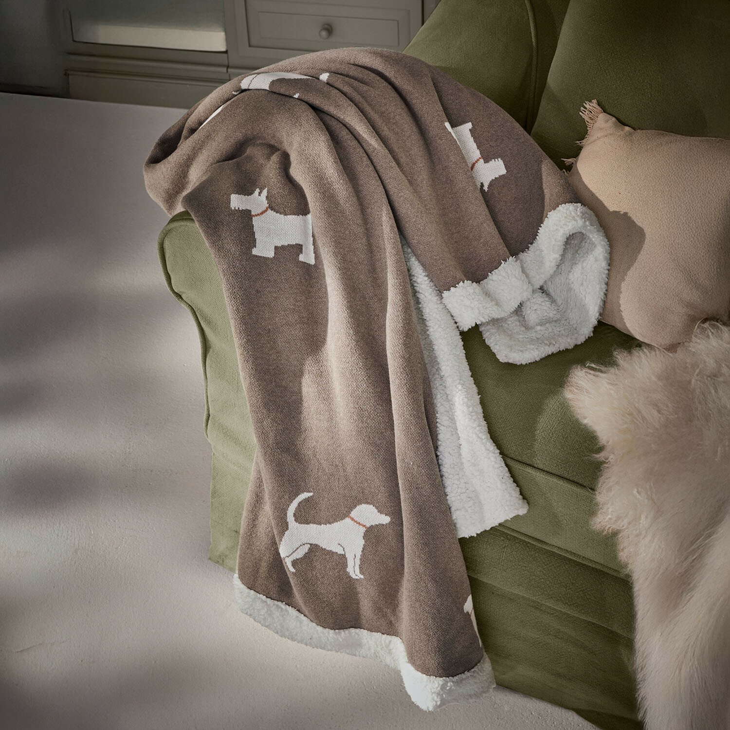 Huisdierendeken Olyden Bruine deken met witte fleece voering en witte hondenpatronen op groene bank, zacht en decoratief