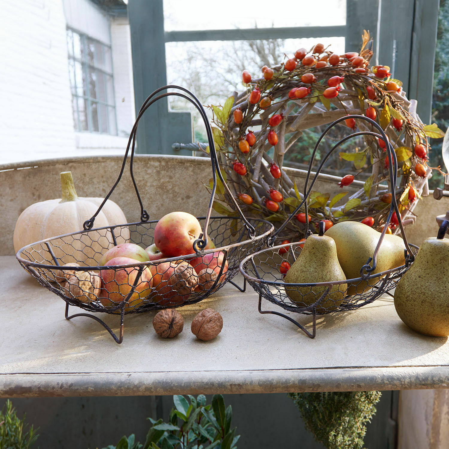 Mand set van 2 Serrie Twee metalen fruitmanden met handvatten gevuld met appels en peren, rustieke herfstdecoratie