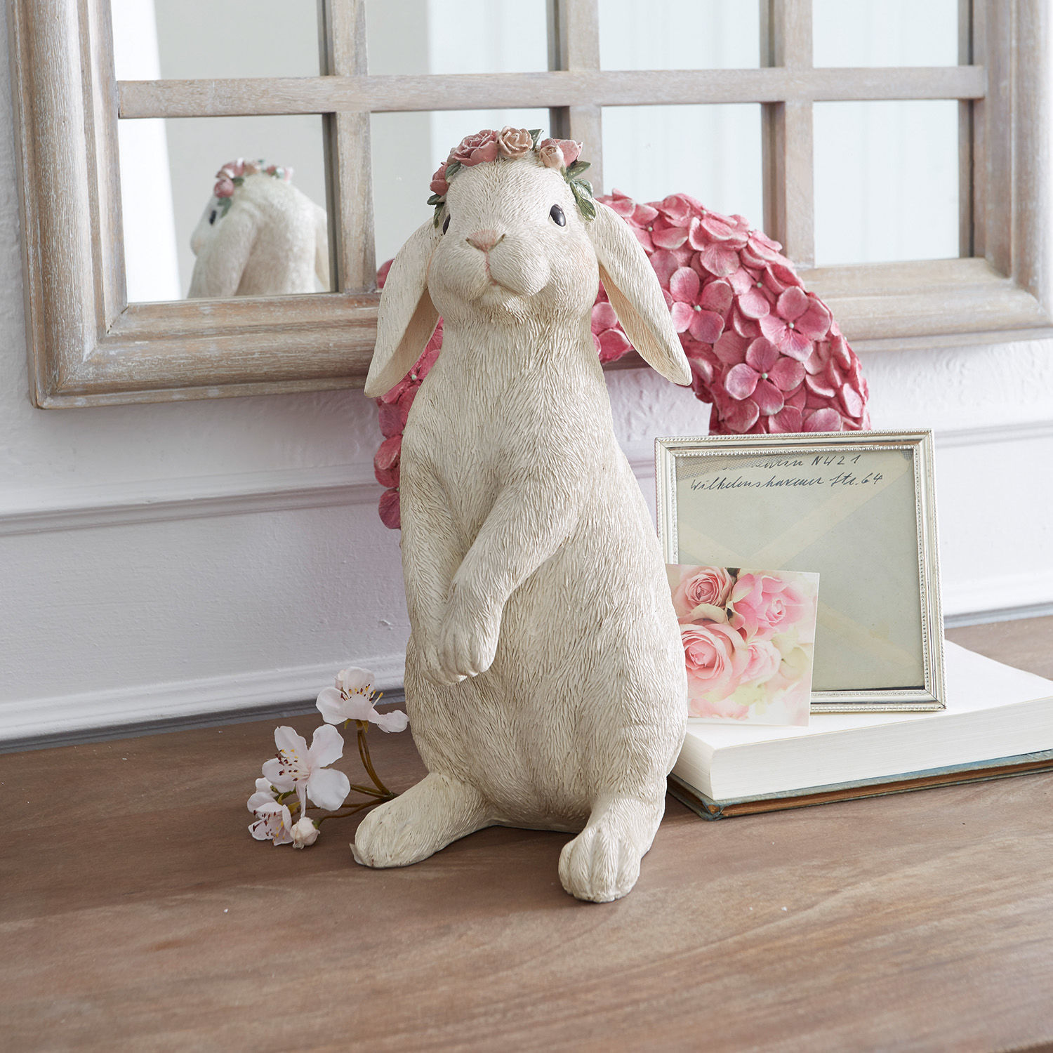 Lapin Sweety Figurine de lapin crème en matériau avec couronne de fleurs roses sur une table décorée