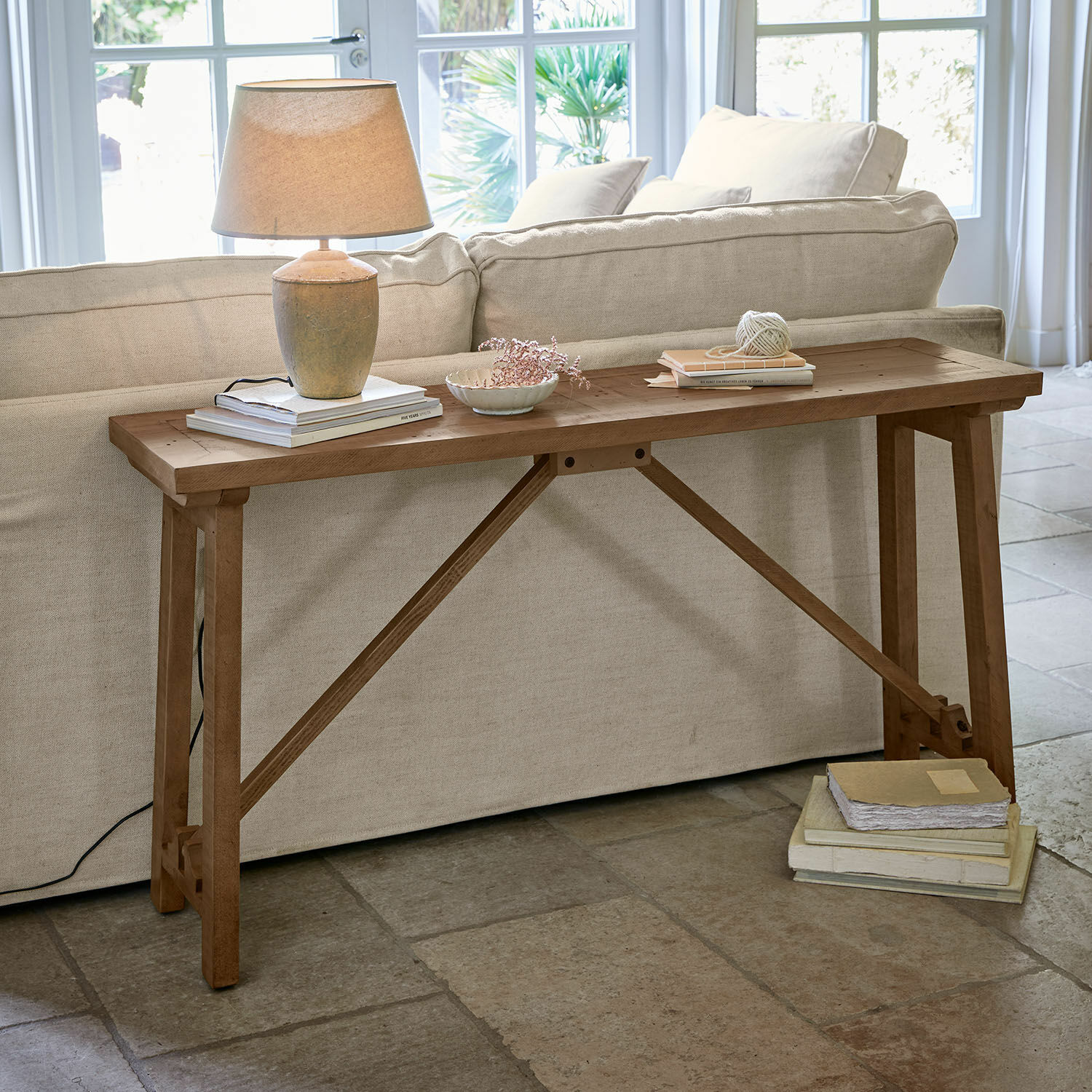 Sidetable Flemming Houten tafel in natuurlijke kleur achter bank met lamp en boeken, stijlvolle woonkamermeubel
