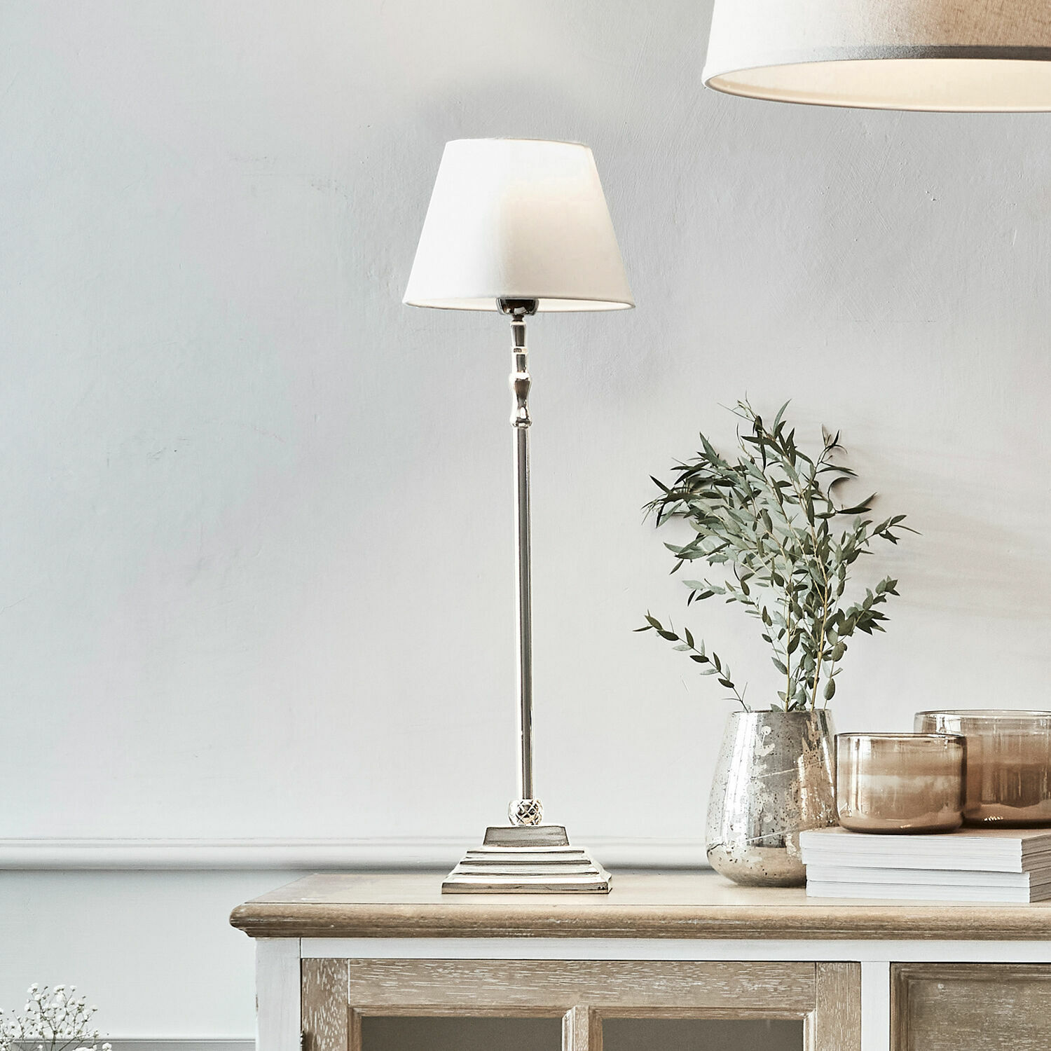 Tafellamp Mayfair Elegante tafellamp met witte kap en metalen voet op houten kast, interieurdecoratie