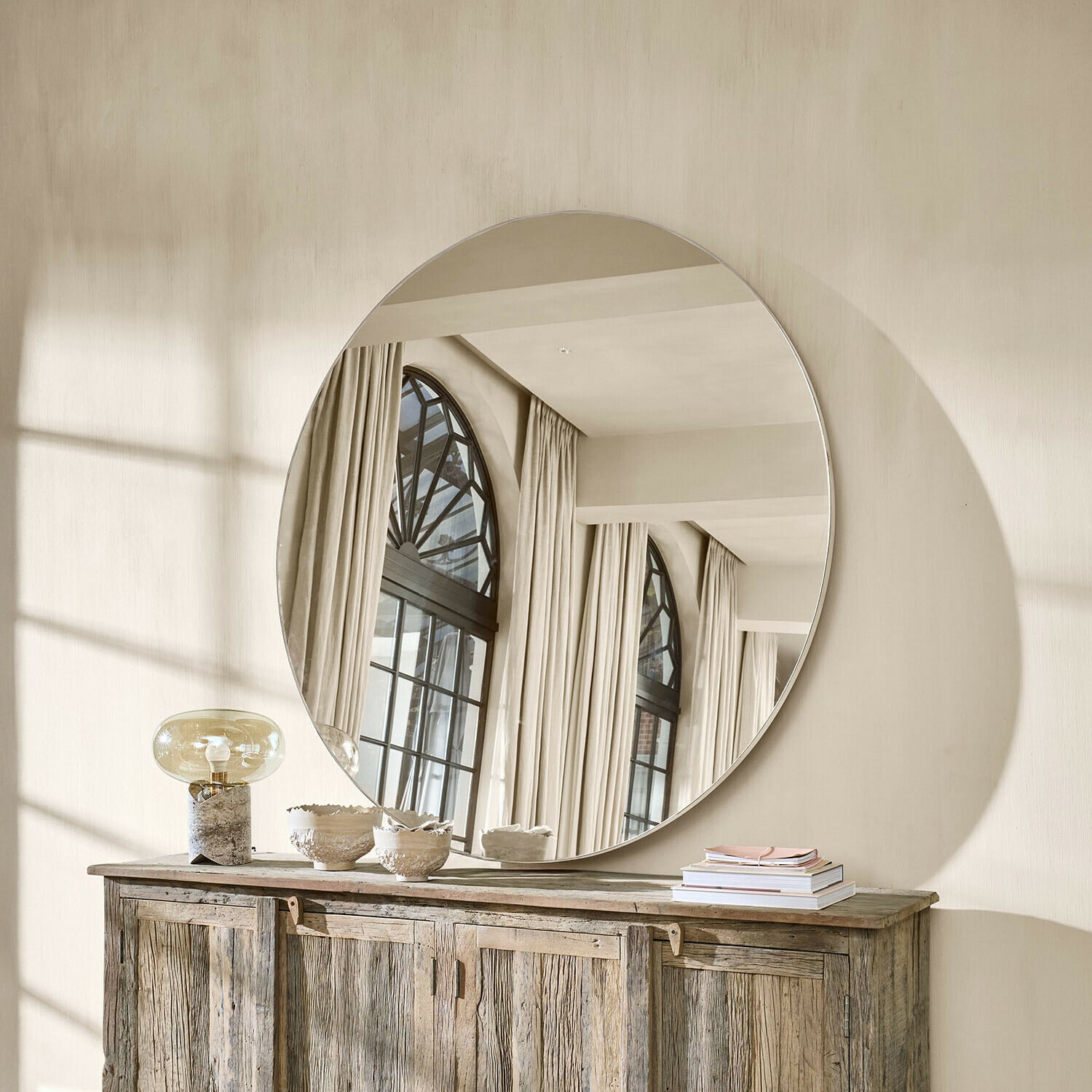 Miroir Roulène Grand miroir rond suspendu au-dessus d'un buffet en bois dans un intérieur lumineux naturel