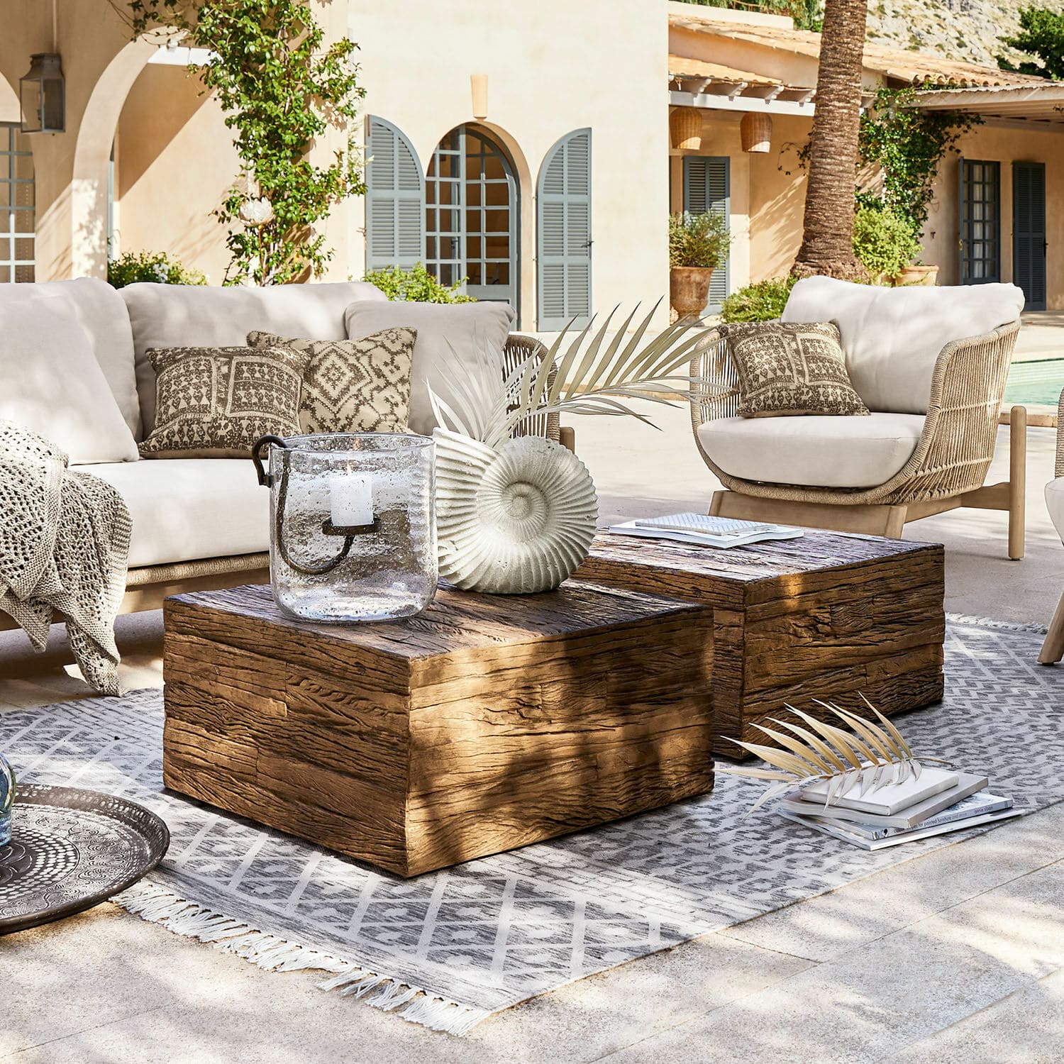 Table basse Glâne Ensemble de mobilier de jardin avec coussins clairs et tables basses en bois sur tapis gris en terrasse